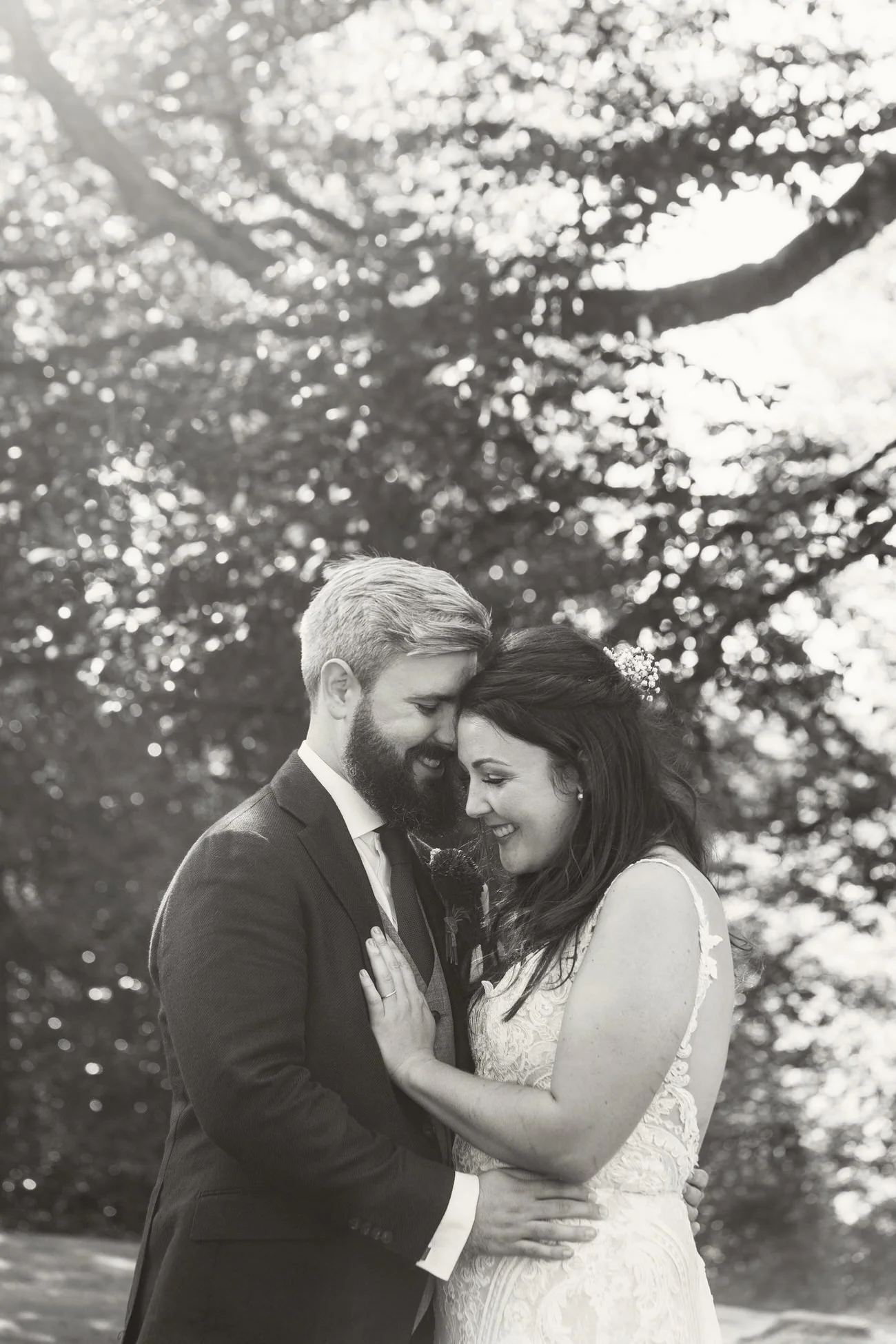 Bride and groom touching heads laughing at Fairyhill wedding venue. Surrounded by forestry.
