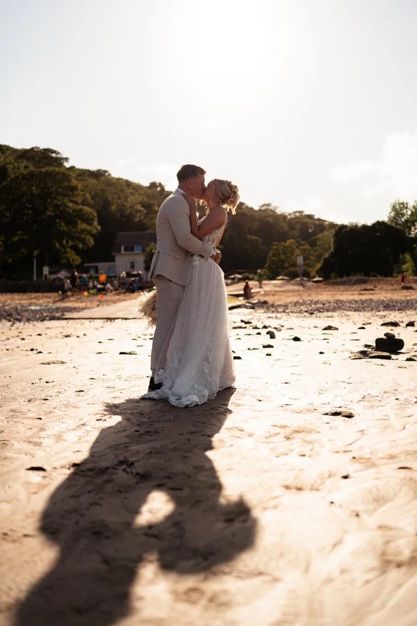 Couple kissing in golden hour sun on their wedding day at the Oxwich Bay hotel in Swansea.
