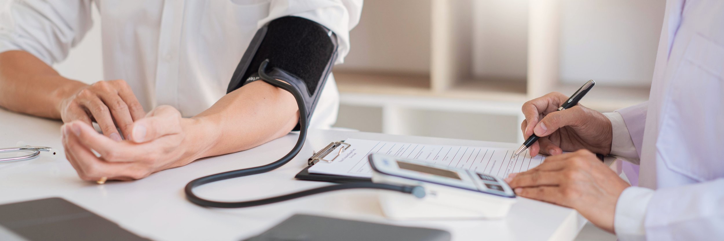 Doctor taking blood pressure and making clinical notes during a cardiology appointment, WE Cardiology, London
