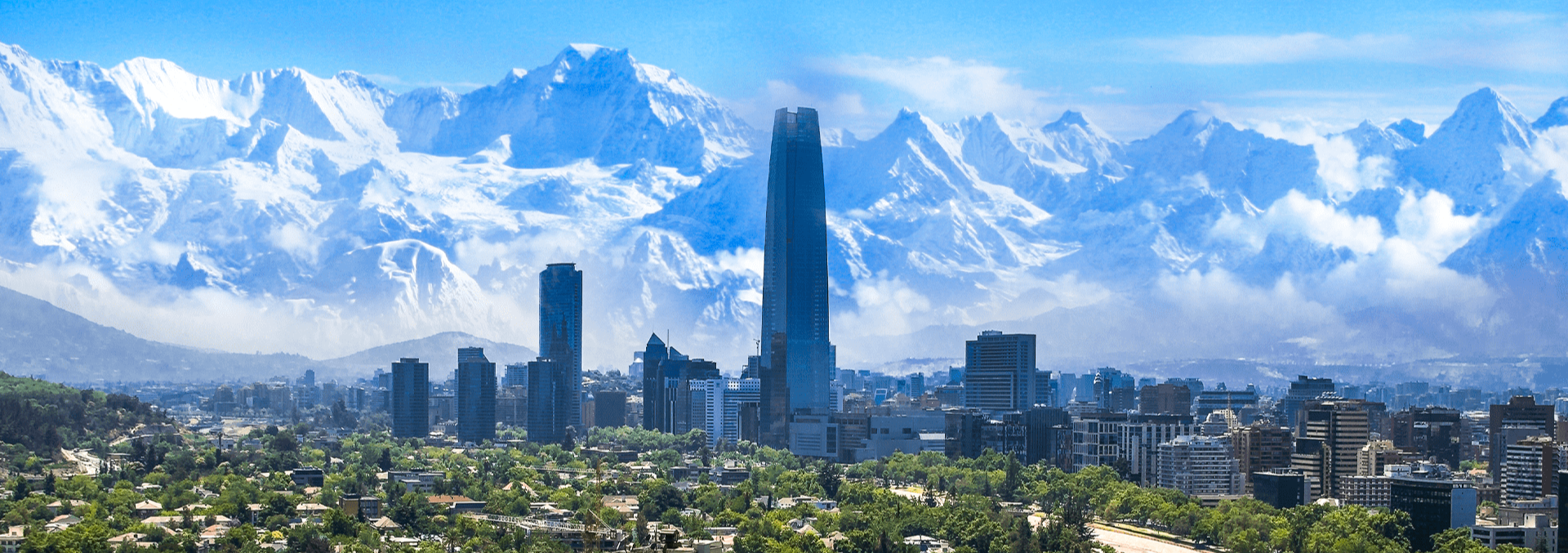Vista do centro de Santiago do Chile com prédios altos e montanhas nevadas ao fundo.