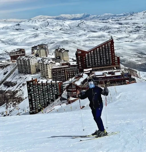 Pessoa esquiando na neve com vista de edifícios e montanhas ao fundo