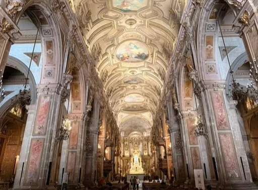 Interior de uma igreja barroca com teto decorado, altares ricos e iluminação dourada.