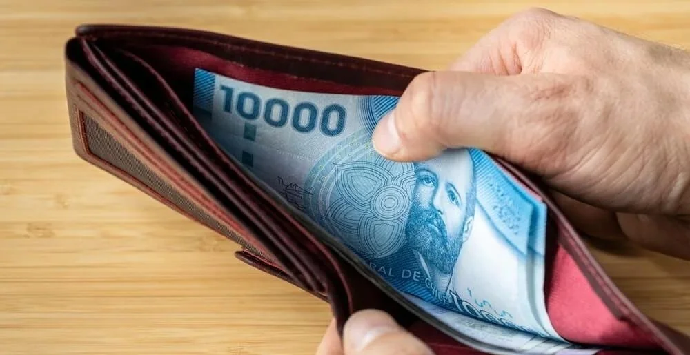 Pessoa segurando uma carteira com uma nota de 1000 pesos dentro.