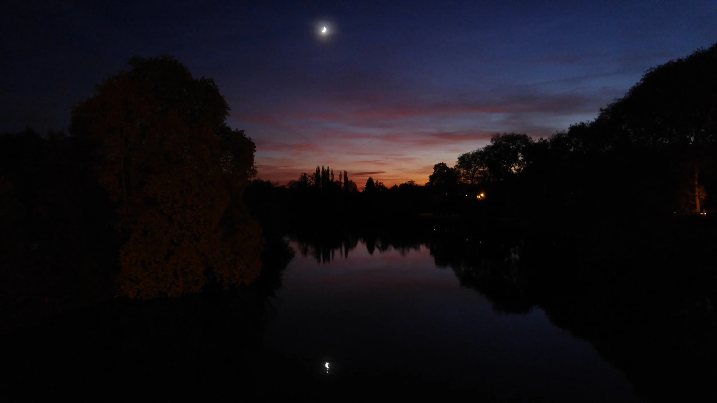 The moon and the last golden rays of sunset reflected on the still waters of the Vienne River at Confolens, France, a magical end to a peaceful evening in this hidden gem of western France.