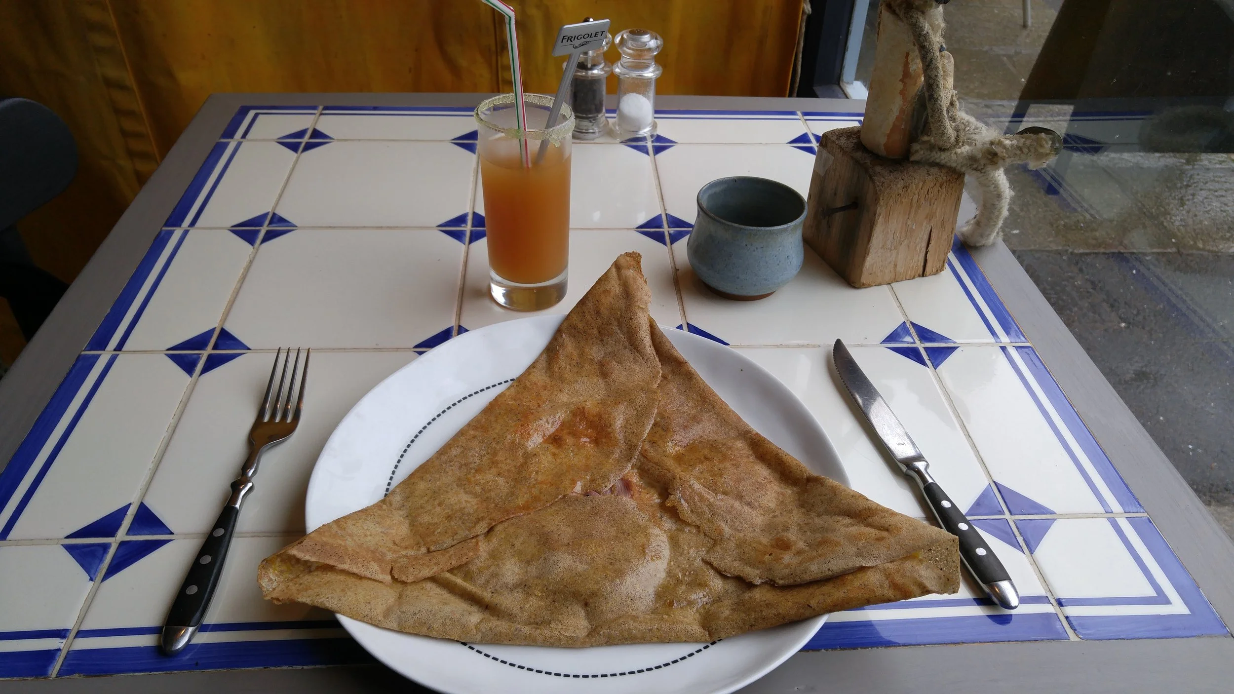 A buckwheat crêpe (galette) that is filled with egg, cheese and meat is often called a “complète” - this Brittany classic is served alongside a cocktail made with local Breton cider at a crêperie in Quimper, France.