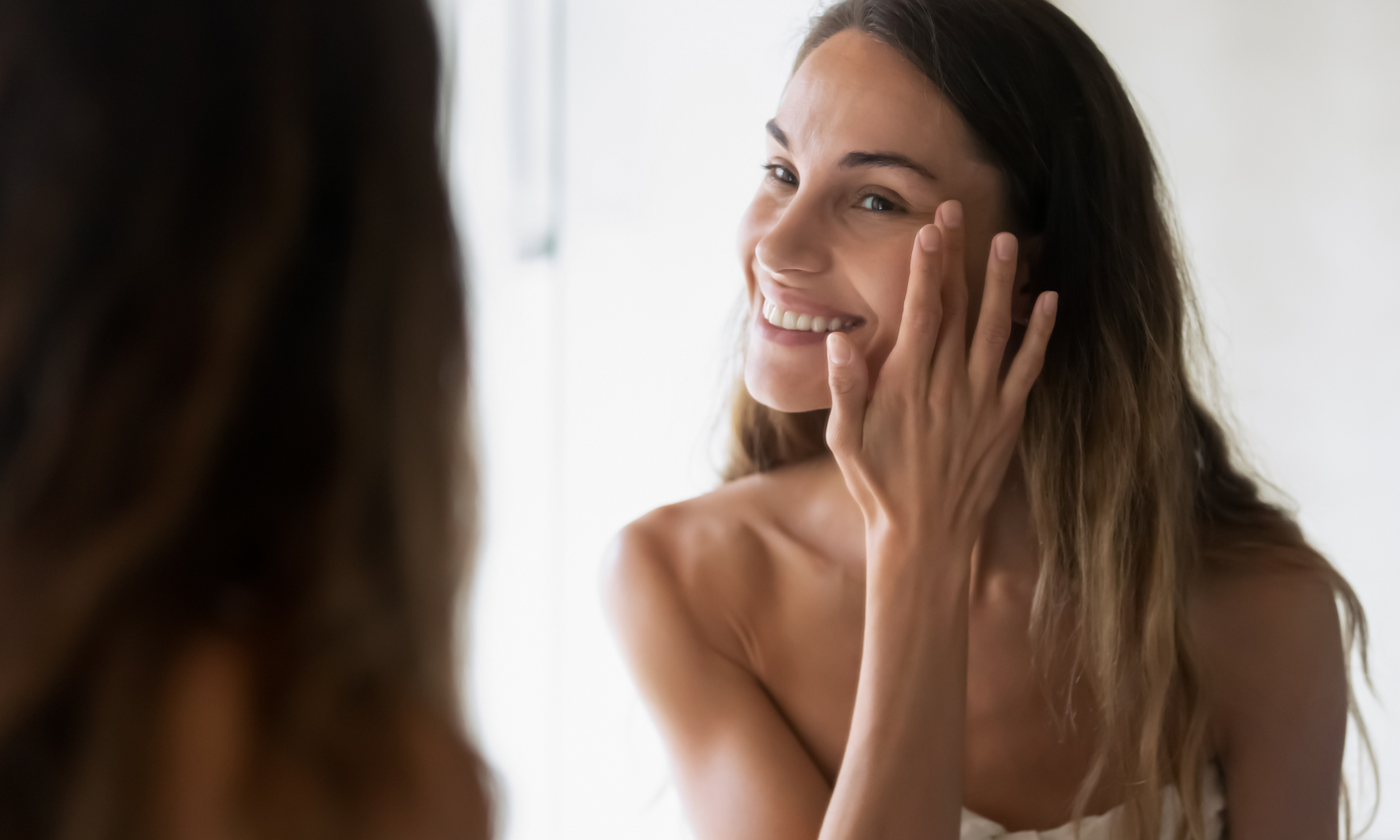 woman looking in mirror after fillers at mae aesthetics in midlothian