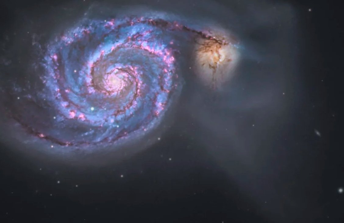 An image of a galaxy with a spiral shape, vibrant pink and purple colors, and surrounding stars in space.