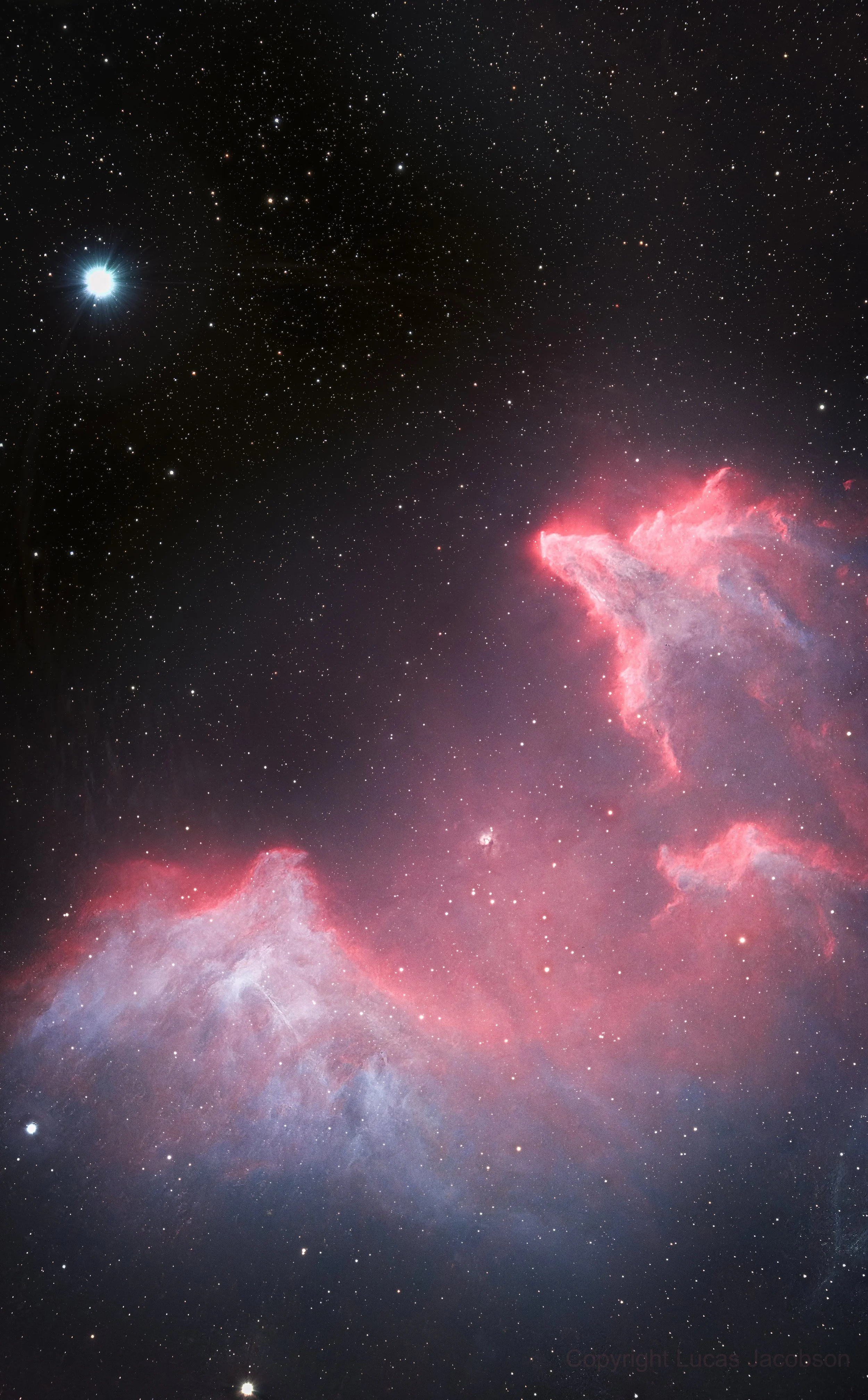 A photograph of space featuring numerous stars, a bright star on the left, and a prominent pink and purple nebula on the bottom right.