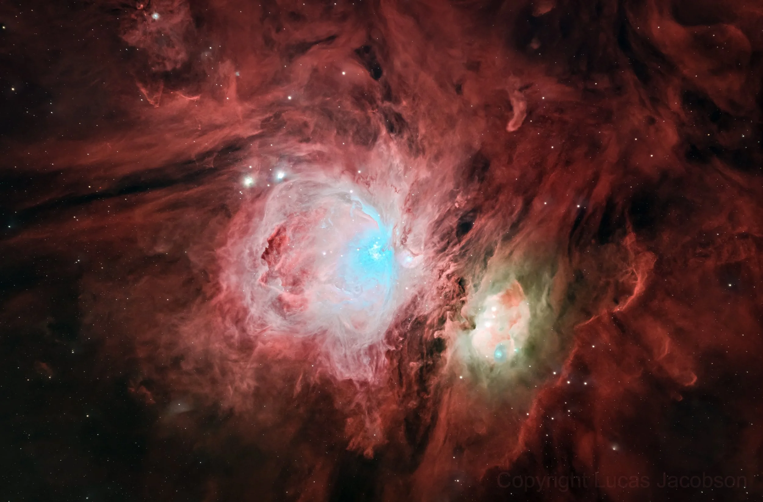 A deep space image of the Orion Nebula showing bright stars, red and pink colored gas clouds, and dark dust lanes.