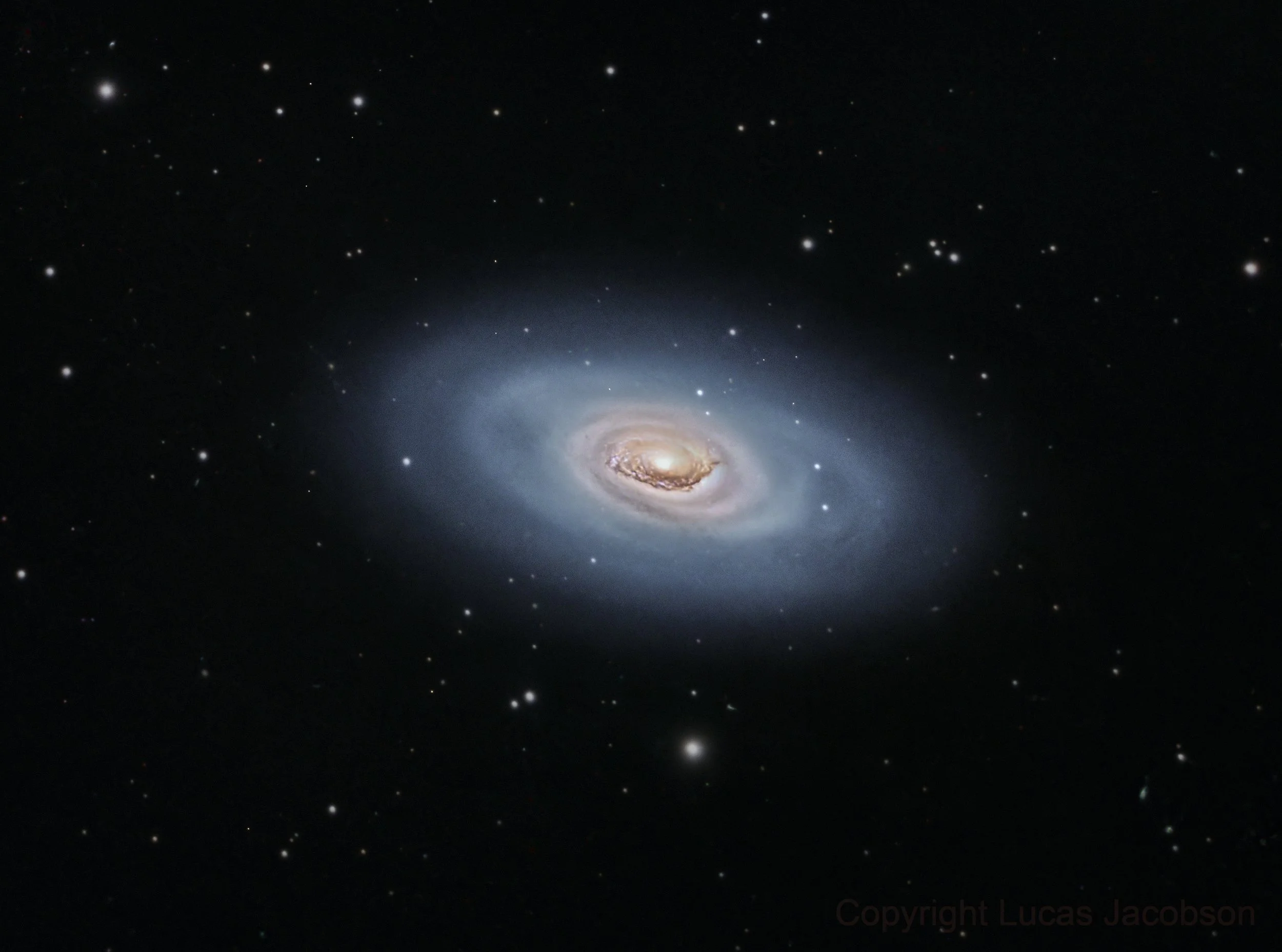 Deep space image showing a bright galaxy with a spiral structure, surrounded by numerous stars and cosmic dust.