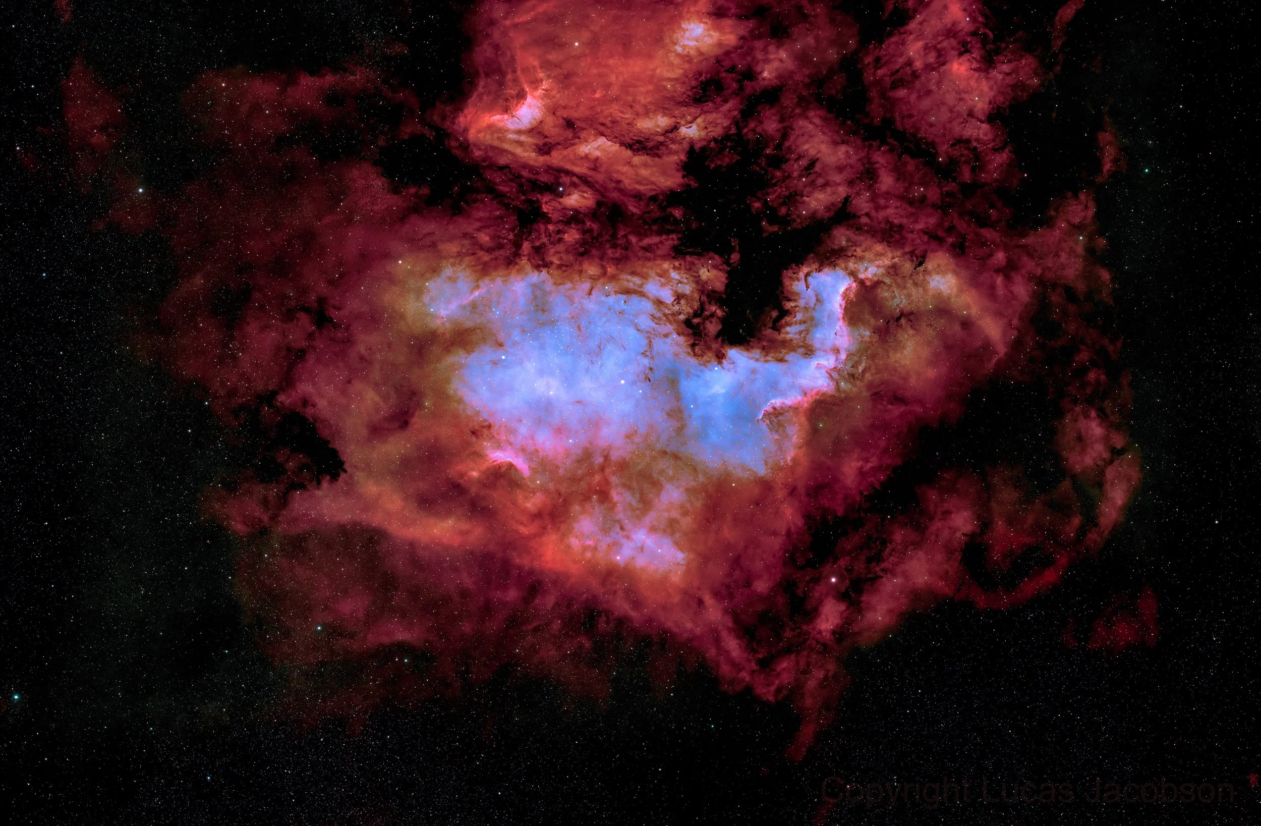 Colorful nebula in deep space with red, pink, blue, and purple hues, surrounded by stars.