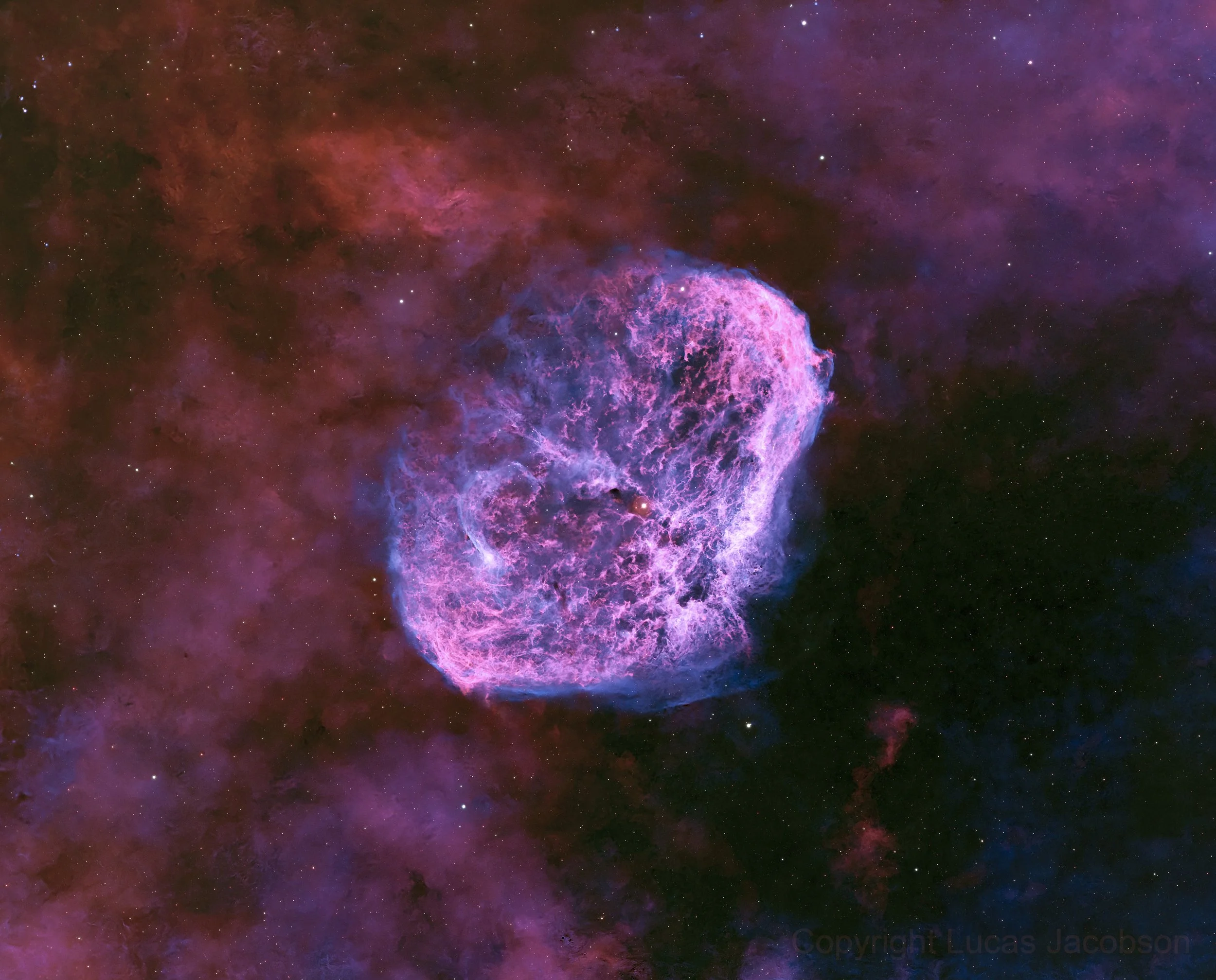 A vibrant nebula in outer space with pink, purple, and red hues, scattered with stars.