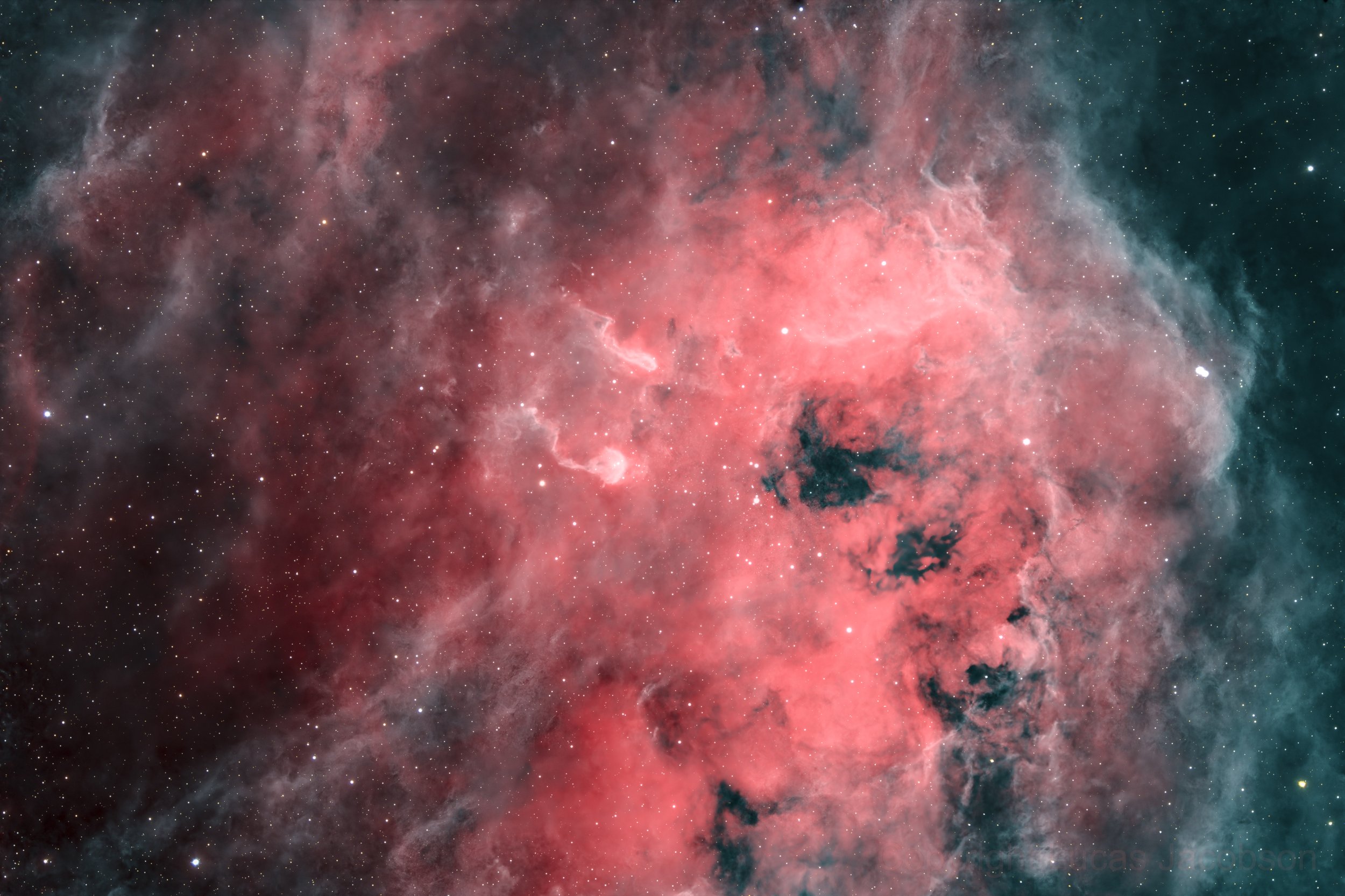 A vibrant image of a nebula in outer space with Pink, red, and greenish hues, featuring numerous small white stars scattered throughout.