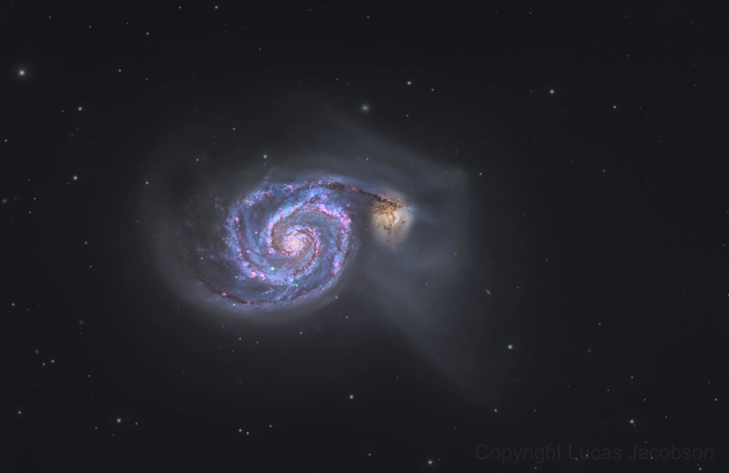 An image of a galaxy with a spiral shape, vibrant pink and purple colors, and surrounding stars in space.