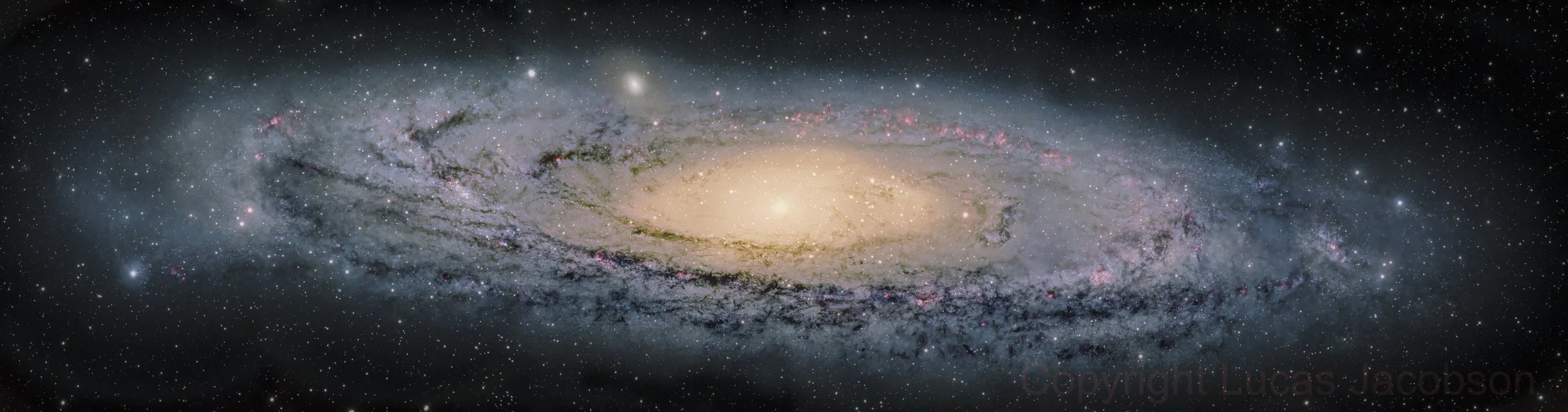 A wide view of a galaxy with a bright central core and spiral arms filled with stars, dust, and pink nebulae, set against a backdrop of numerous smaller stars.