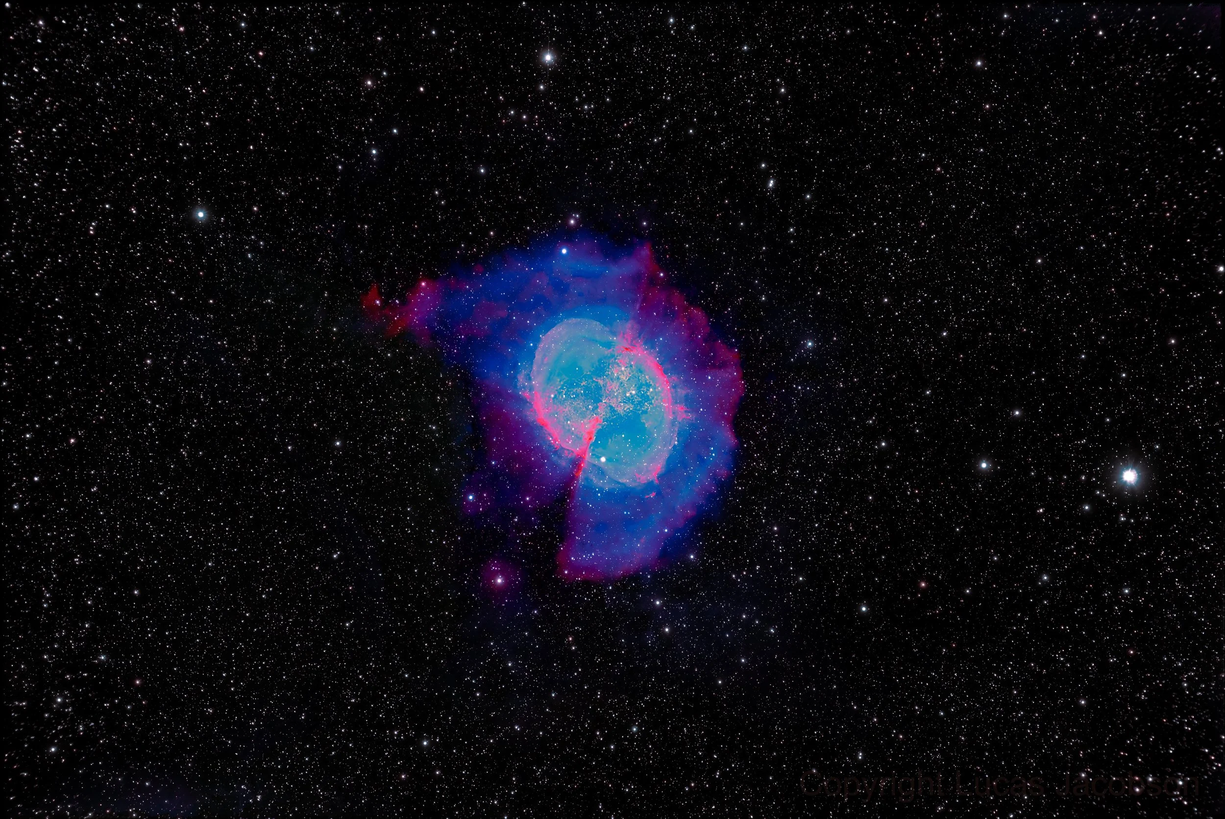 A deep space photograph of a colorful nebula with stars scattered throughout the background.