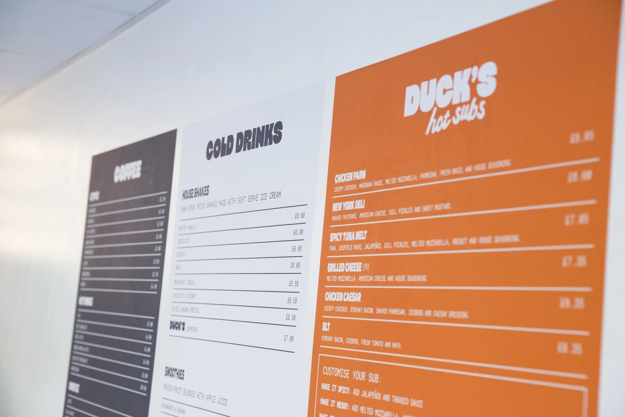 Close-up of a restaurant menu listing food categories like 'Cold Drinks' and 'Ducks Hot Subs' with various menu items and prices.
