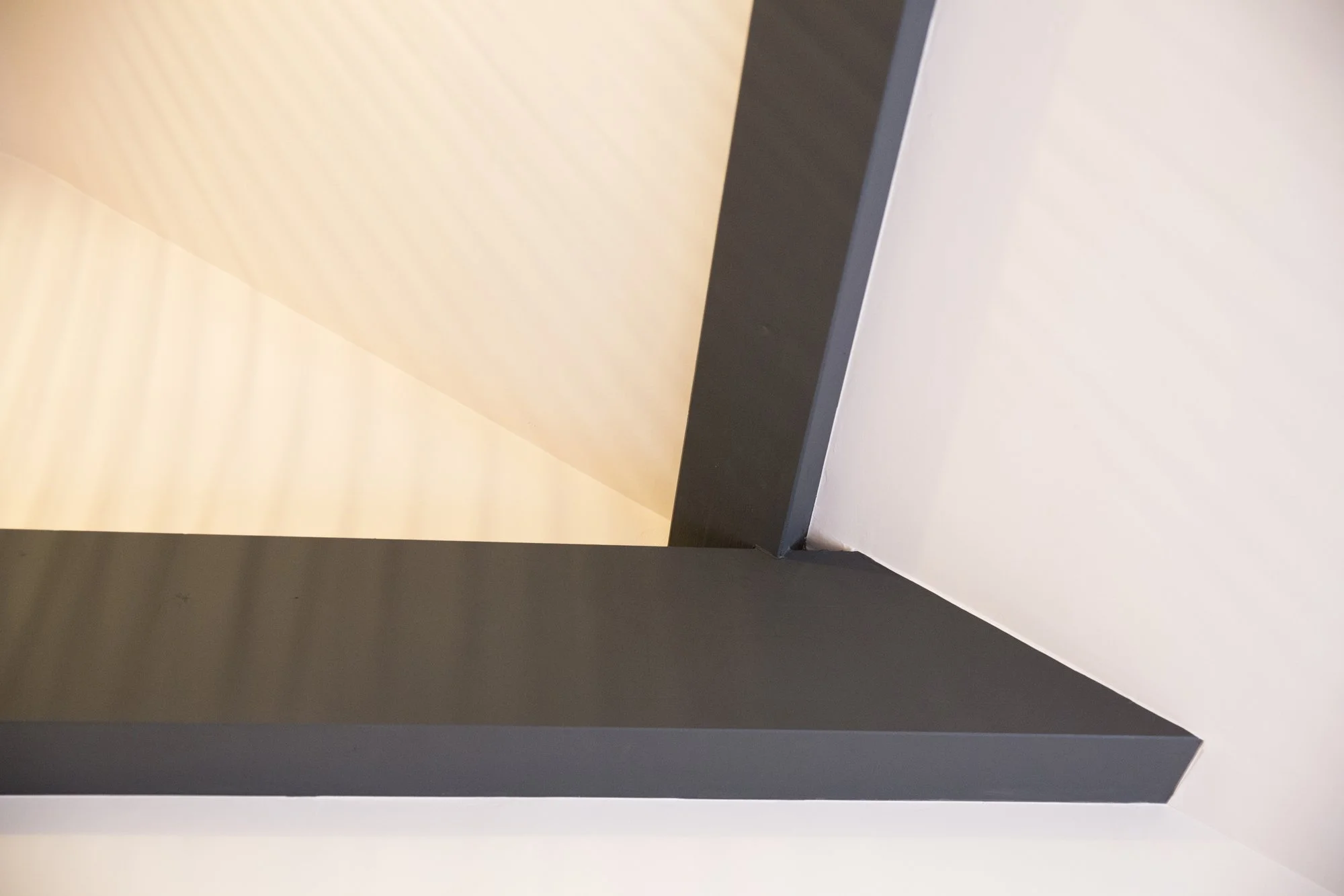 Close-up of a corner of a room showing a black door frame and white walls, with a beige ceiling.