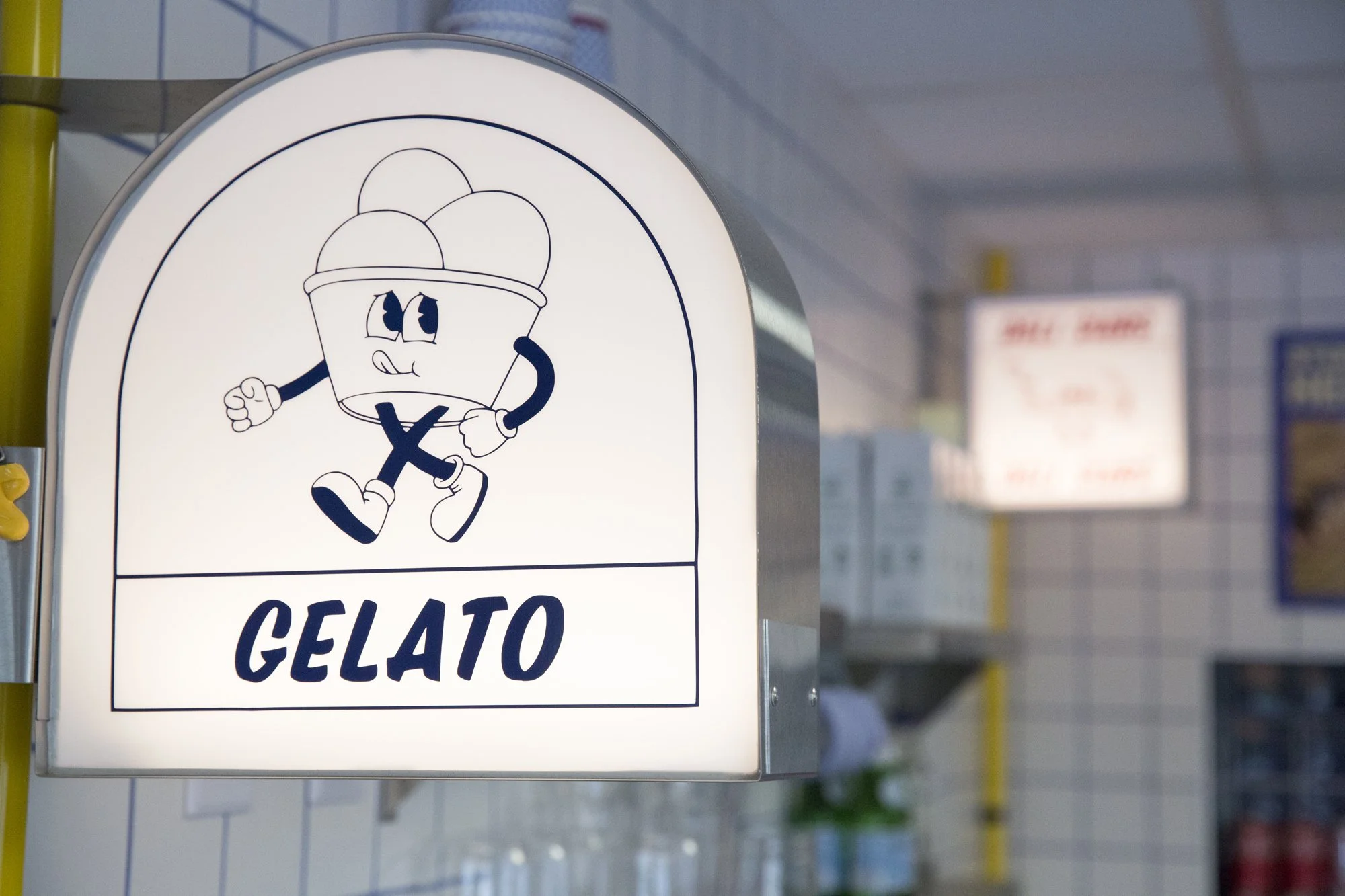 Sign with a cartoon ice cream cone character and the words 'Gelato'.