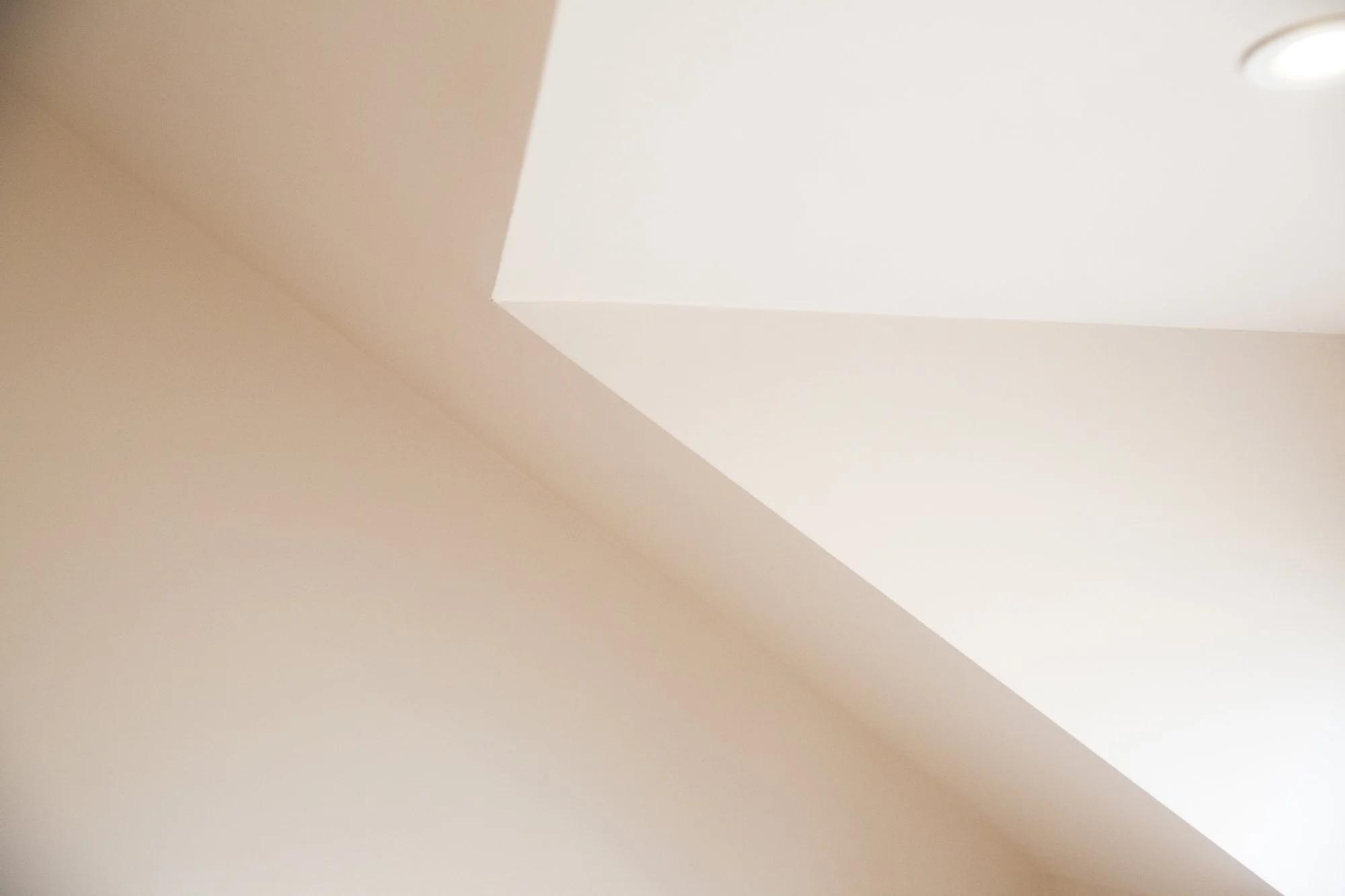 Close-up of a ceiling with a white ceiling light fixture in the corner.