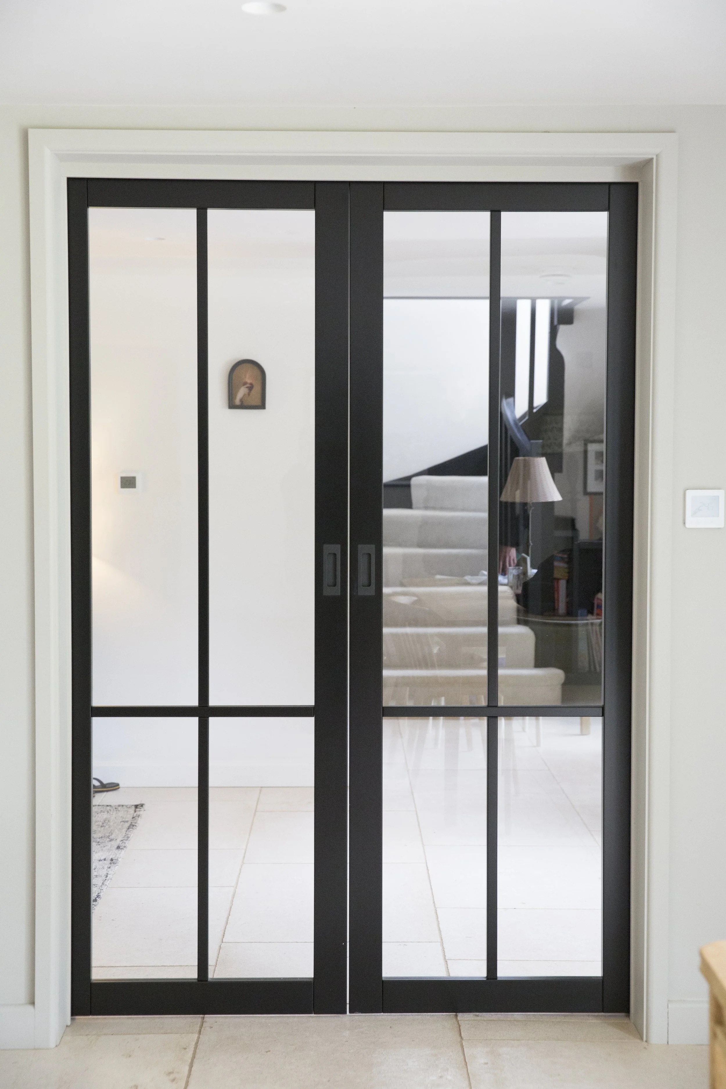 Sliding glass door with black frame separating interior and exterior spaces in a modern home.
