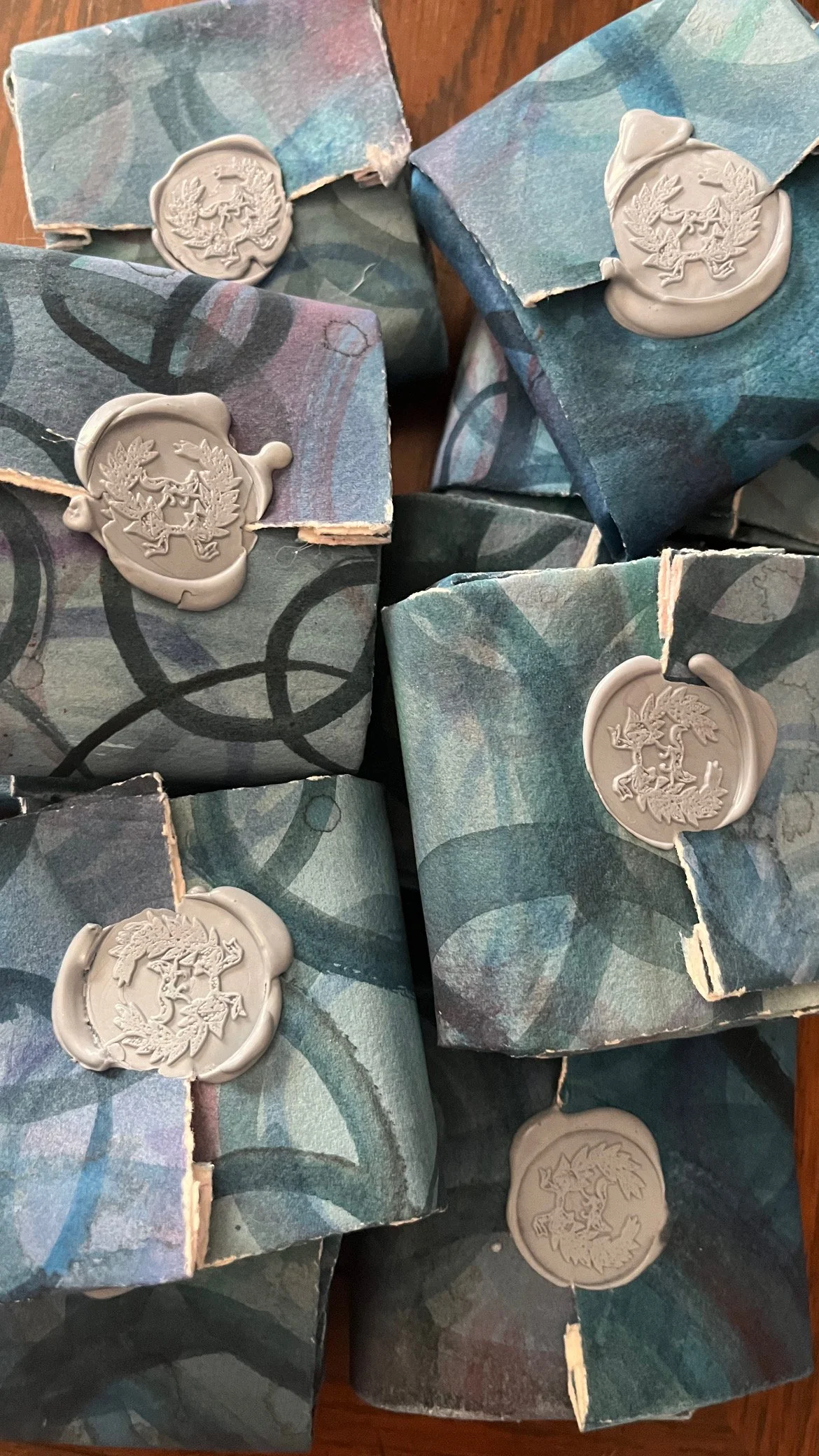 Several wrapped packages with a blue, green, and purple marbled pattern, each sealed with a white wax emblem featuring a crest with a lion and trees.
