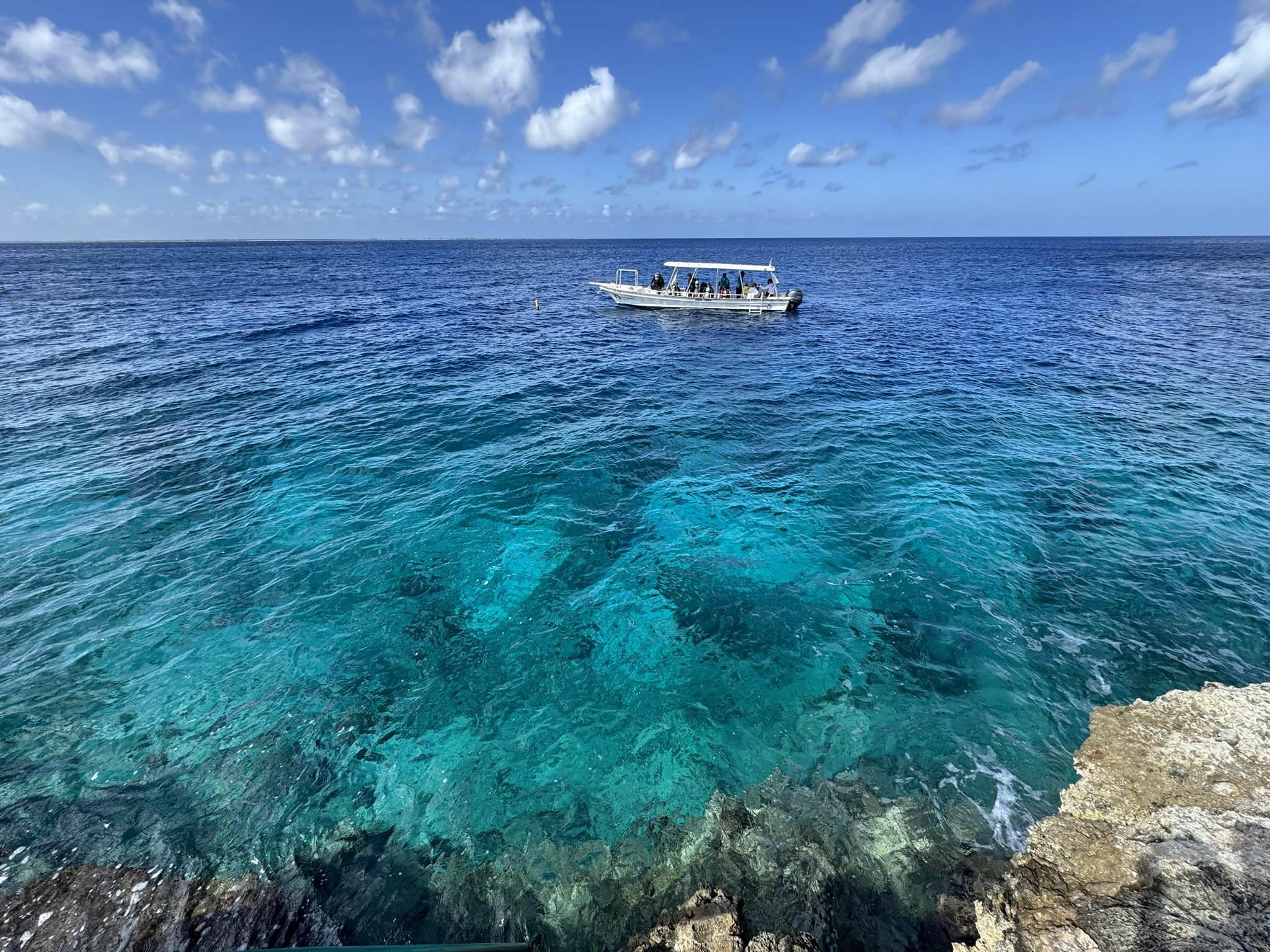 Small dive boat floating over clear turquoise water in the ABC Islands