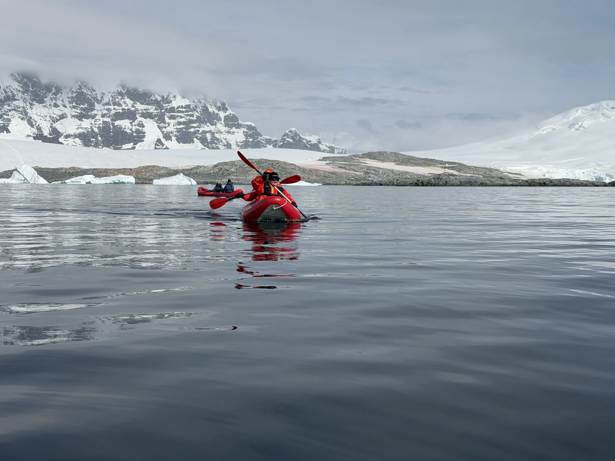  Kayakers exploring Antarctic waters near icebergs   