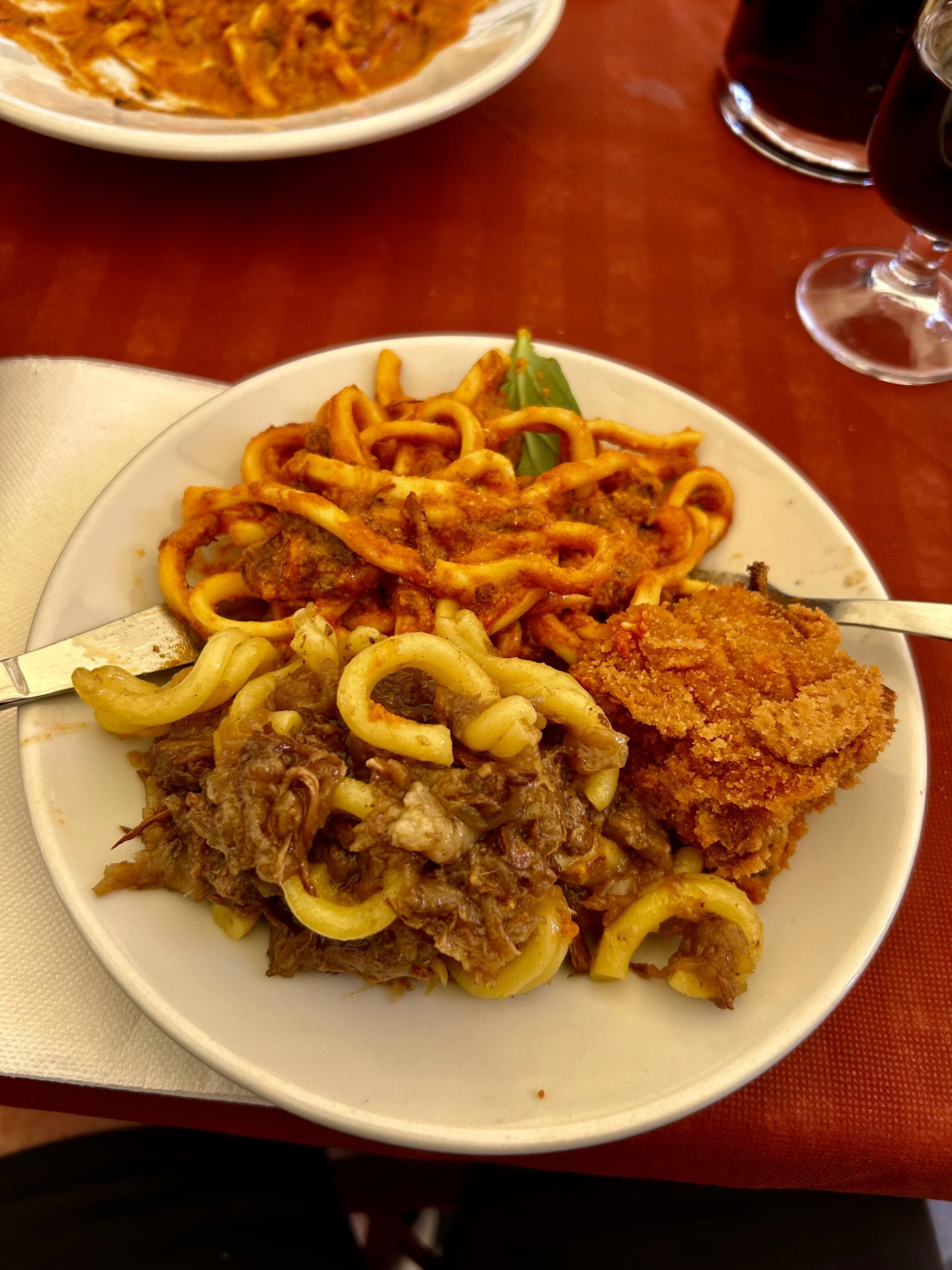 Plate of spaghetti with tomato sauce, fried breaded fish fillet, and a side of cooked vegetables on a white plate.