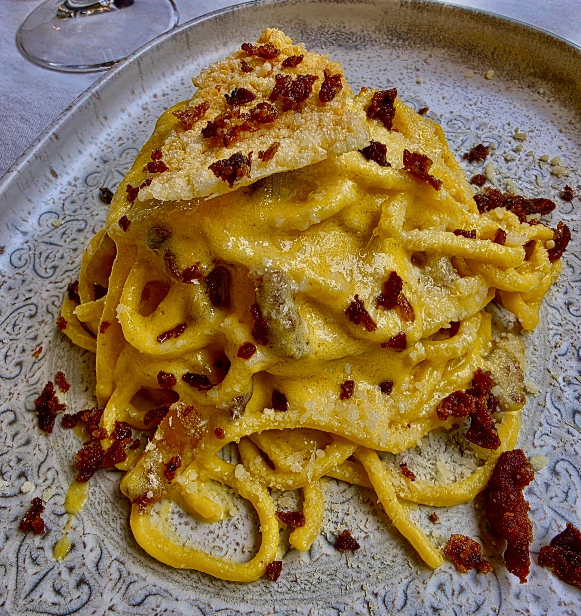 A plate of cooked yellow bell pepper rings topped with crumbled bacon and grated cheese, with a dusting of grated cheese around it.