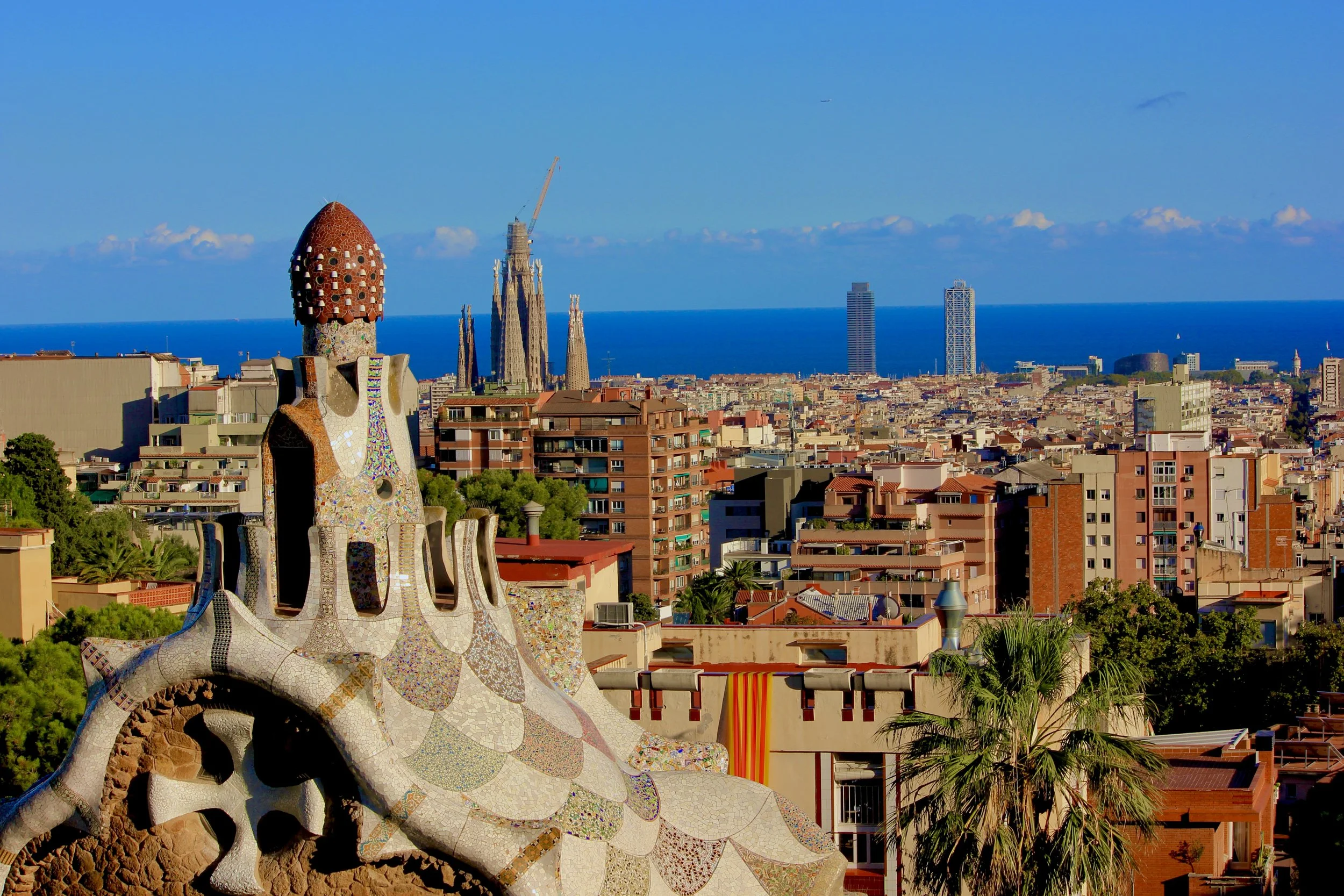 View of Barcelona city skyline with the Sagrada Família church and the sea in the background, taken from a high vantage point.