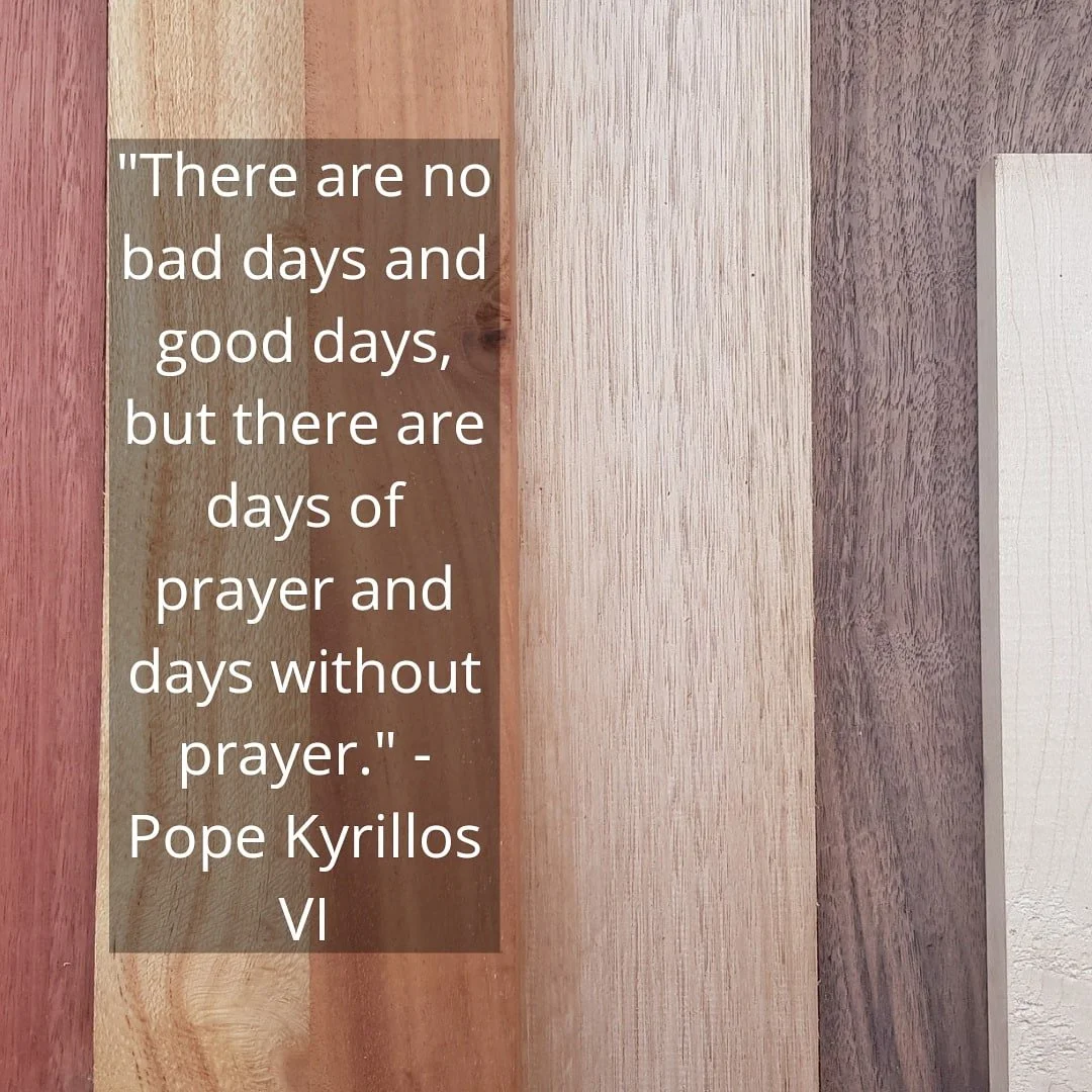 Display of different hardwood timber pieces used, with an overlaid quote in white text on a semi-transparent brown background that reads: "There are no bad days and good days, but there are days of prayer and days without prayer." - Pope Kyrillos VI.