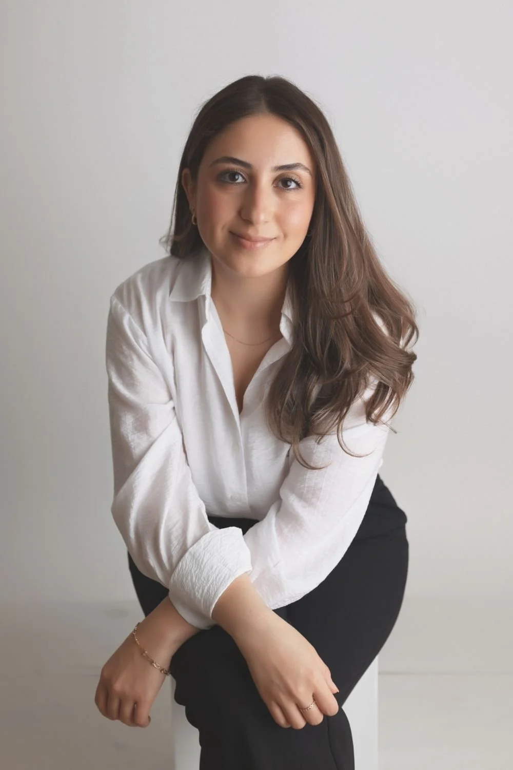 Full body shot of Shabnam sitting on a chair leaning forward