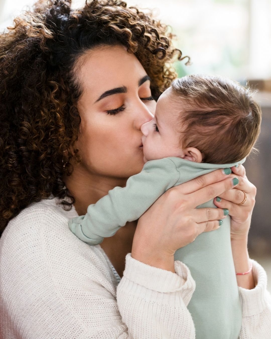 Black mother kissing her newborn baby on the cheek