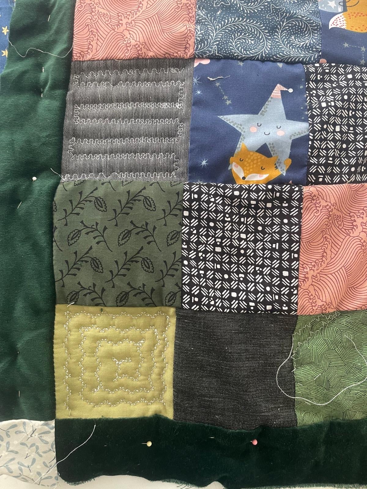 A patchwork quilt made of various fabric squares with different colors and patterns, including floral, geometric, and whimsical designs.
