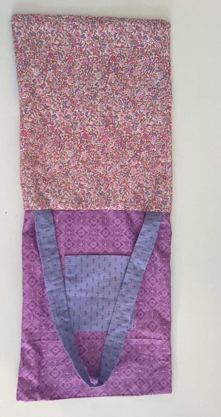 A quilted fabric bag with a pink floral pattern on the upper part and a purple geometric pattern on the lower part, featuring a V-shaped opening.