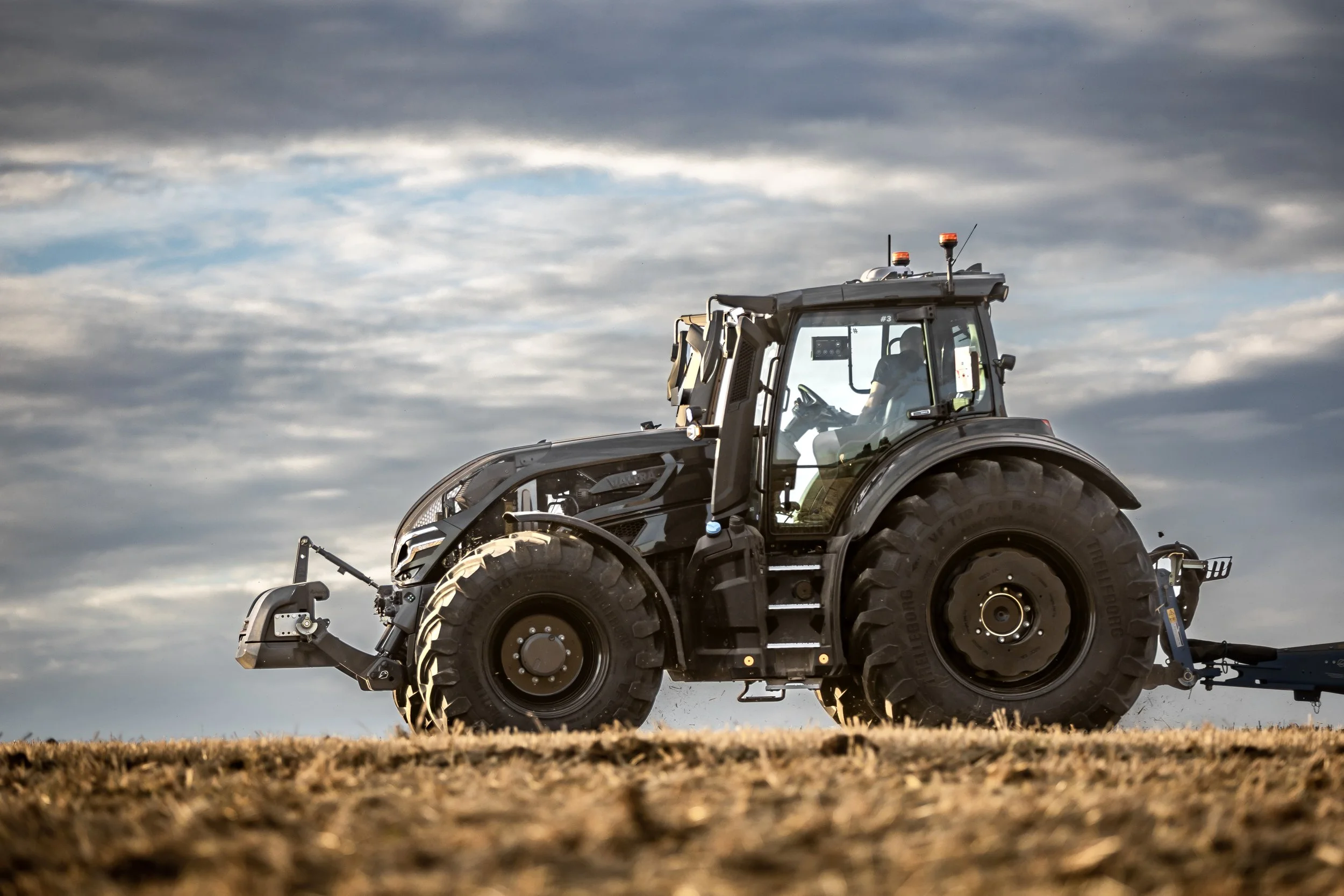 Un tracteur noir VALTRA Q5 dans un champ en travail du sol.