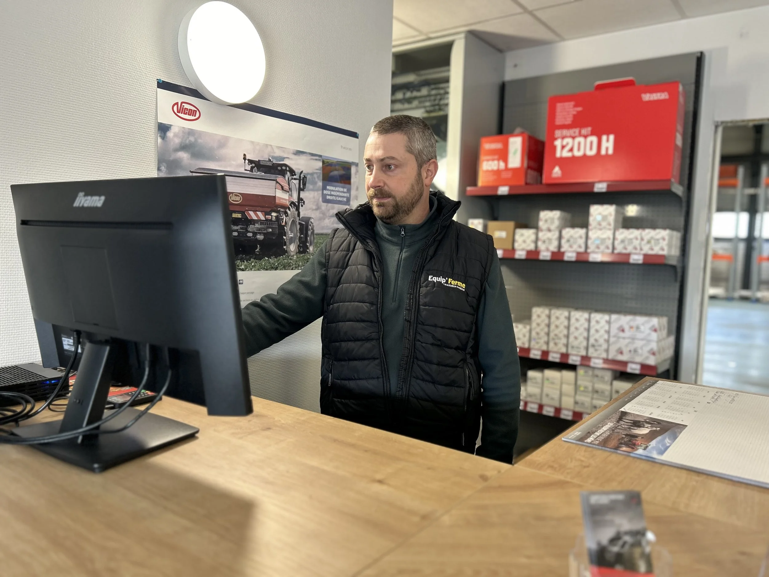 Magasinier agricole ou conseiller technique rentrant les commandes dans l'ordinateur. Il recherche la bonne pièce pour son client agriculteur et vérifie son stock.