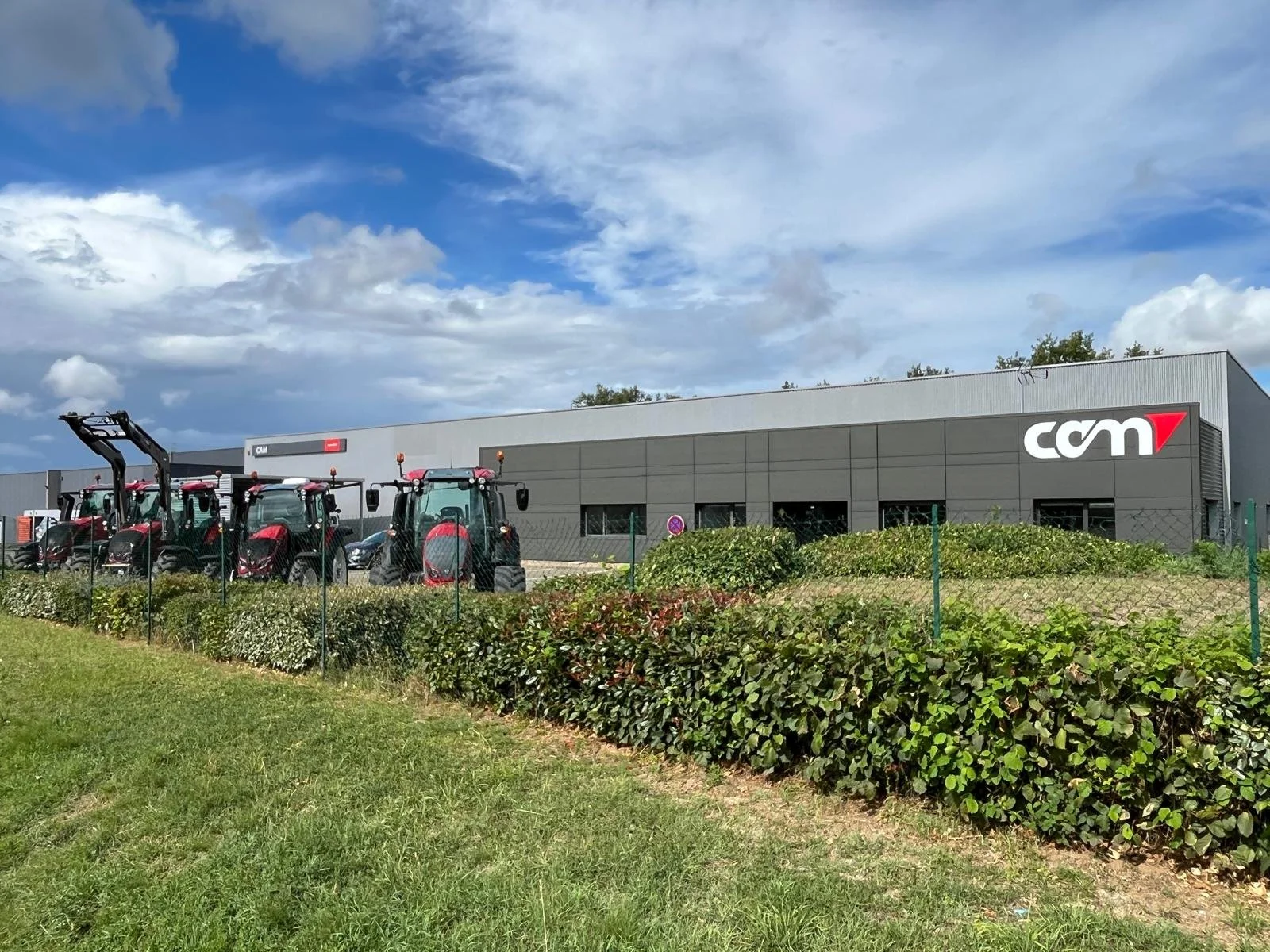 Un bâtiment avec le logo 'CAM'. Distributeur agricole dans le 49. Atelier de réparation, magasin libre-service. Suivi des garanties VALTRA