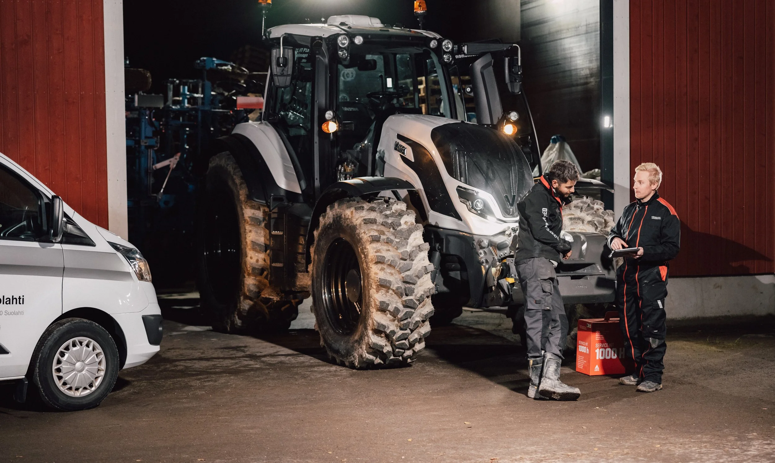 Un technicien agricole discute avec un client agriculteur devant son tracteur. Le mécanicien est en intervention d'entretien sur le tracteur directement sur la ferme du client. Il lui a changé les filtres, vidanger le tracteur, etc.