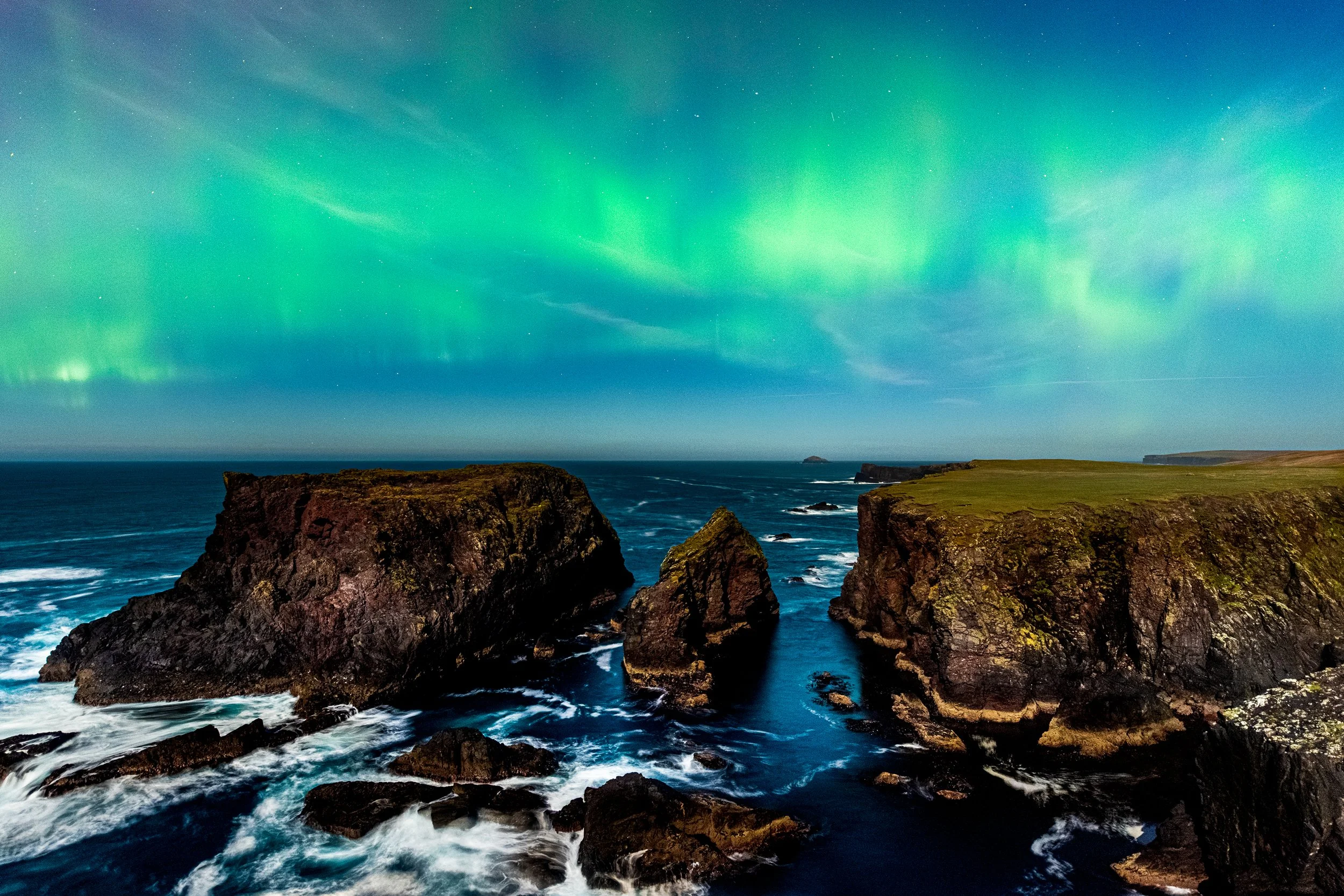 Northern lights dancing about the cliffs and sea stacks at Eshaness, Shetland.
