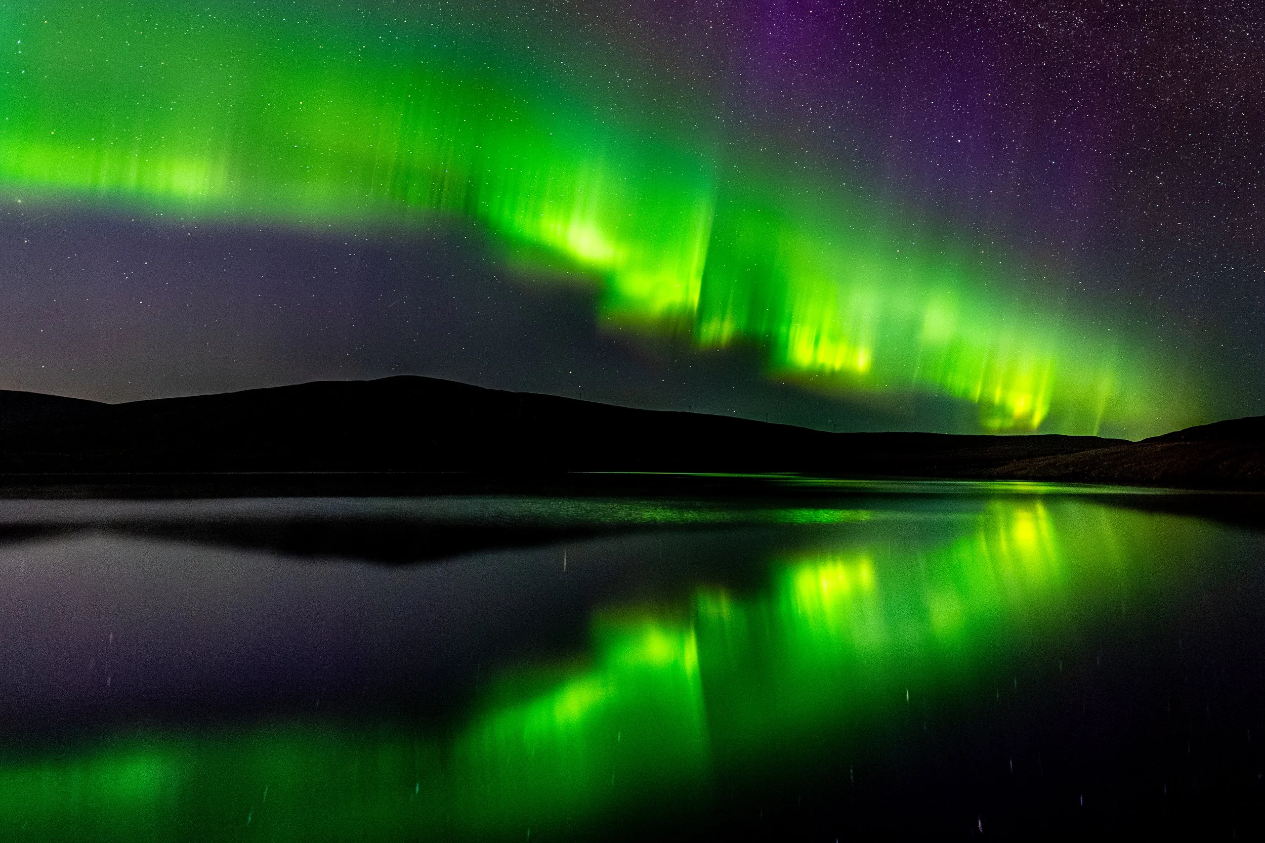Northern lights dancing about a loch in the Shetland Islands.