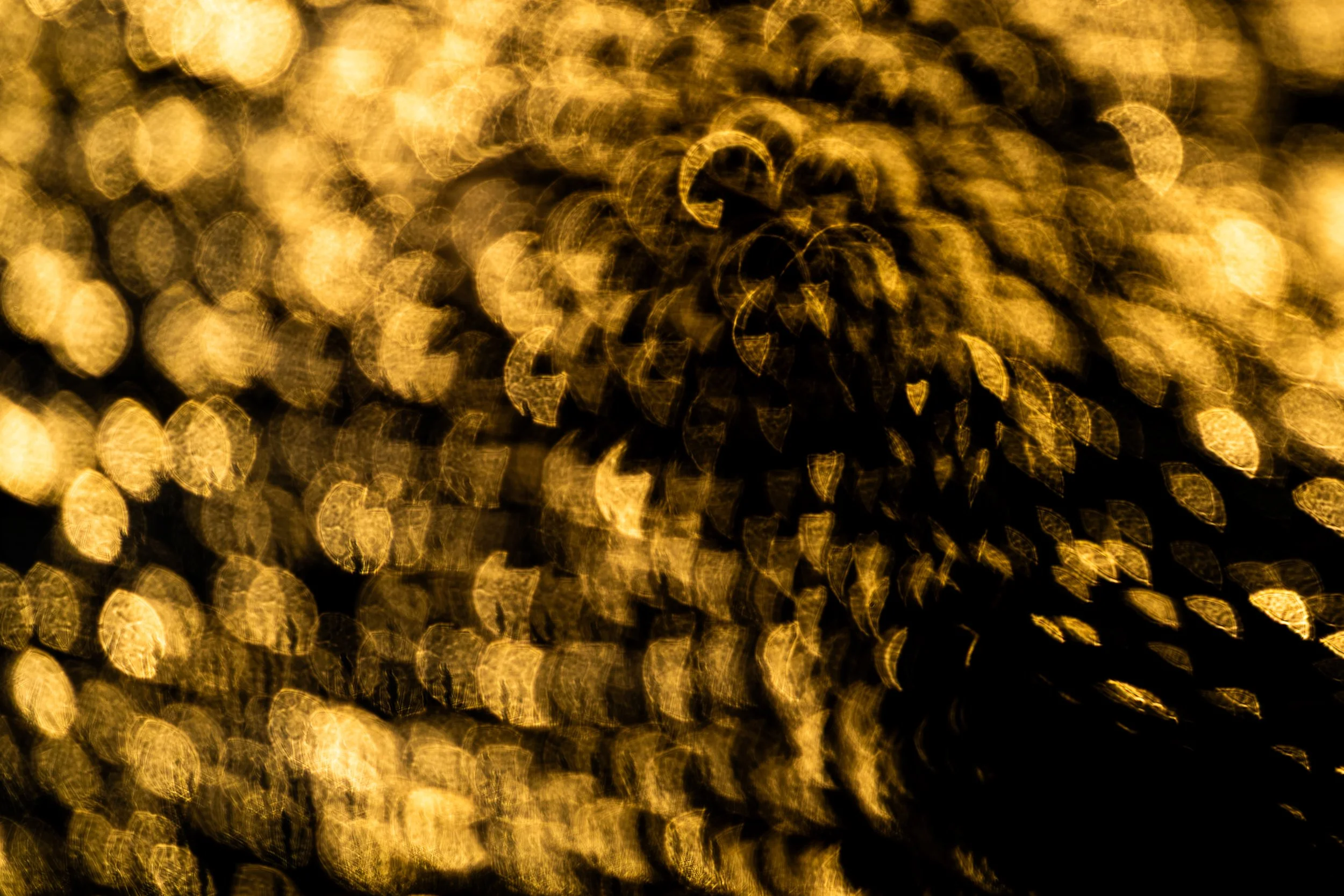 Abstract image of golden bokeh lights creating a tunnel or spiraling effect.