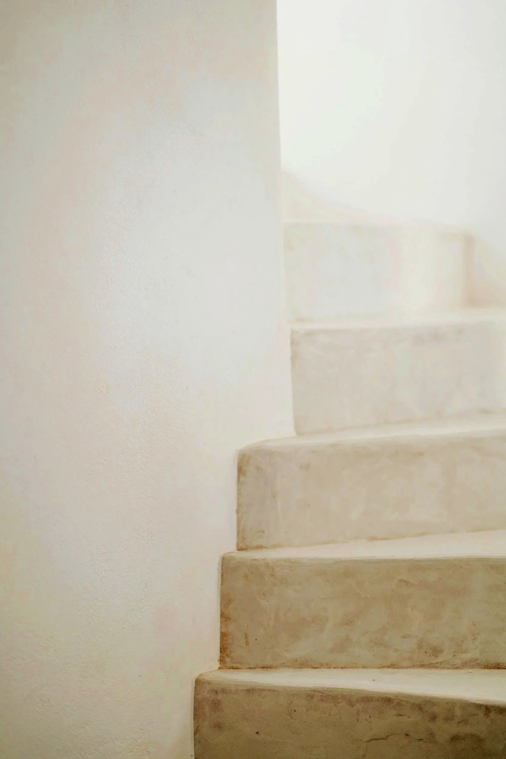 A staircase with beige marble steps next to a plain white wall.