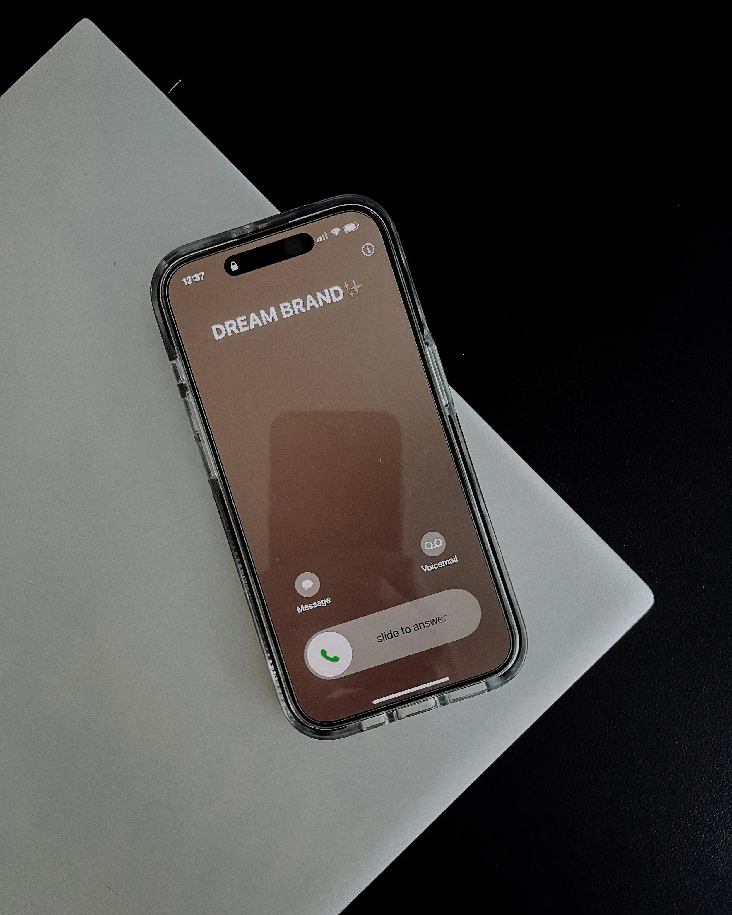 Phone showing an incoming call from a dream brand on a laptop, representing the brand partnership opportunities Brand Curators secures for creators