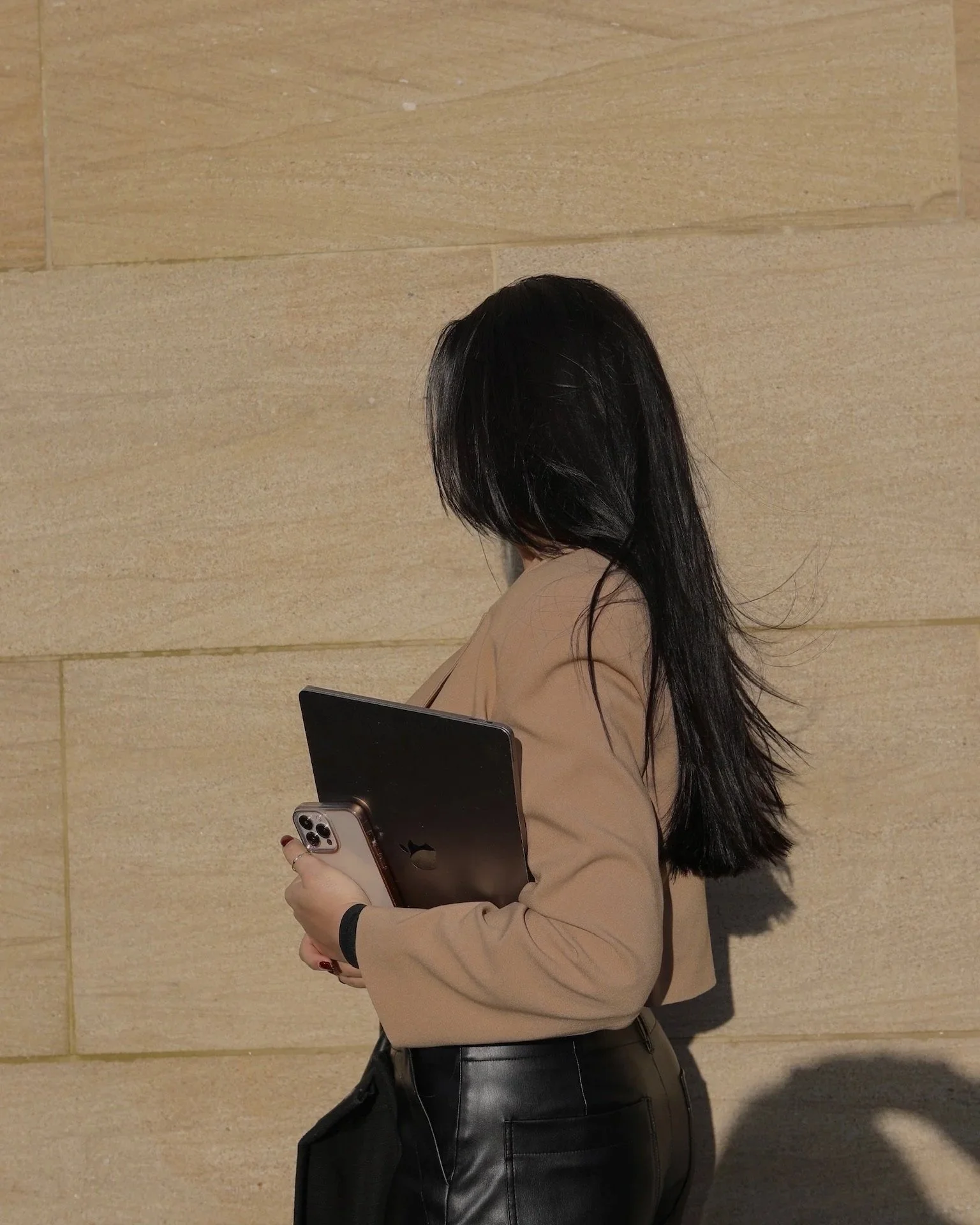 A creatorpreneur carrying a laptop and phone on the go — representing the founders, freelancers, and digital-first talent Brand Curators works with