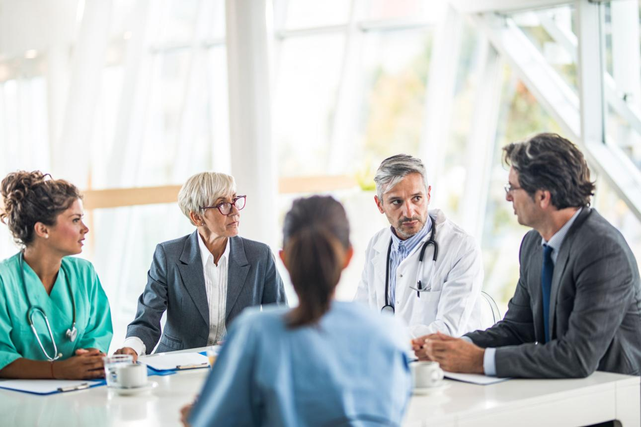 Medical team and a patient in consultation at a hospital or clinic conference table.