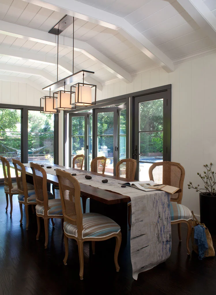 A salvaged walnut table hosts the family dinners. New folding doors open onto the pool deck.  Photography: Leslie Williamson (Copy)