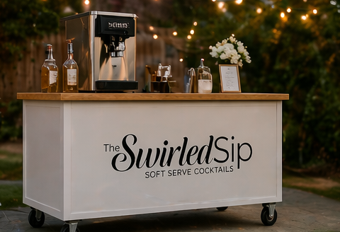 An outdoor cocktail cart with a coffee machine, bottles, glassware, flowers, and a menu, labeled 'The Swirled Sip' for serving cocktails.