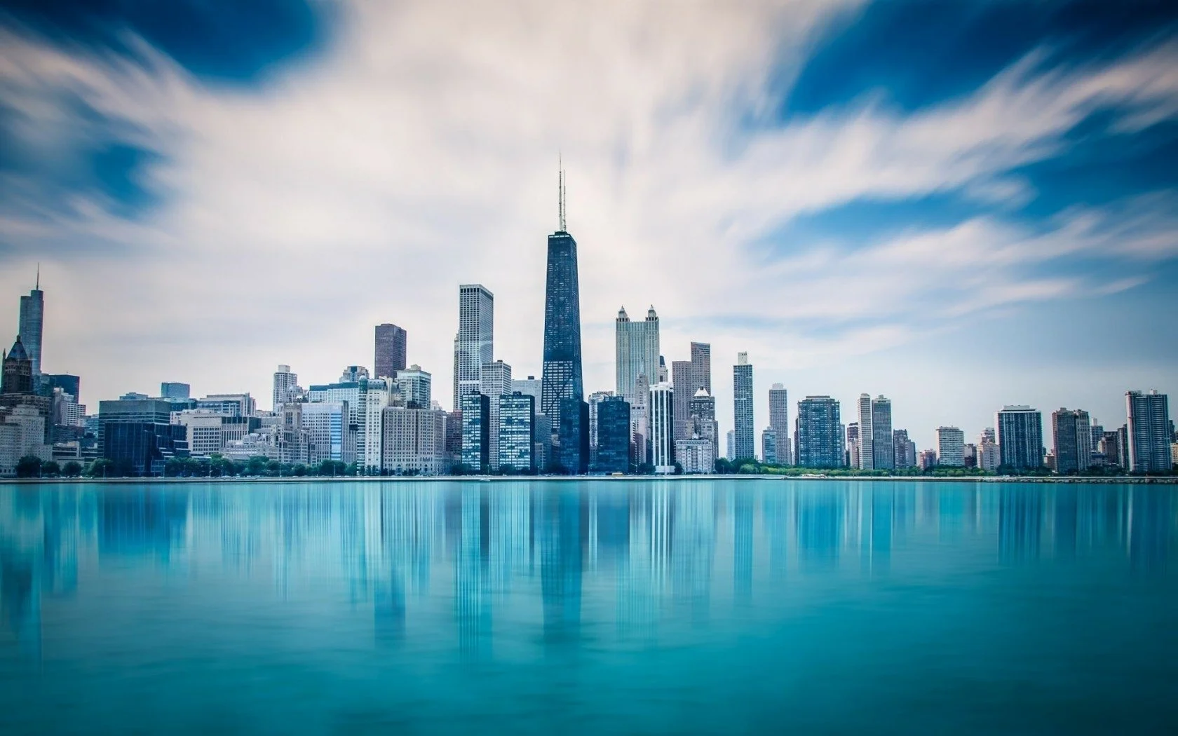 Skyline of Chicago with the Willis Tower and other skyscrapers across Lake Michigan under blue skies with wispy clouds